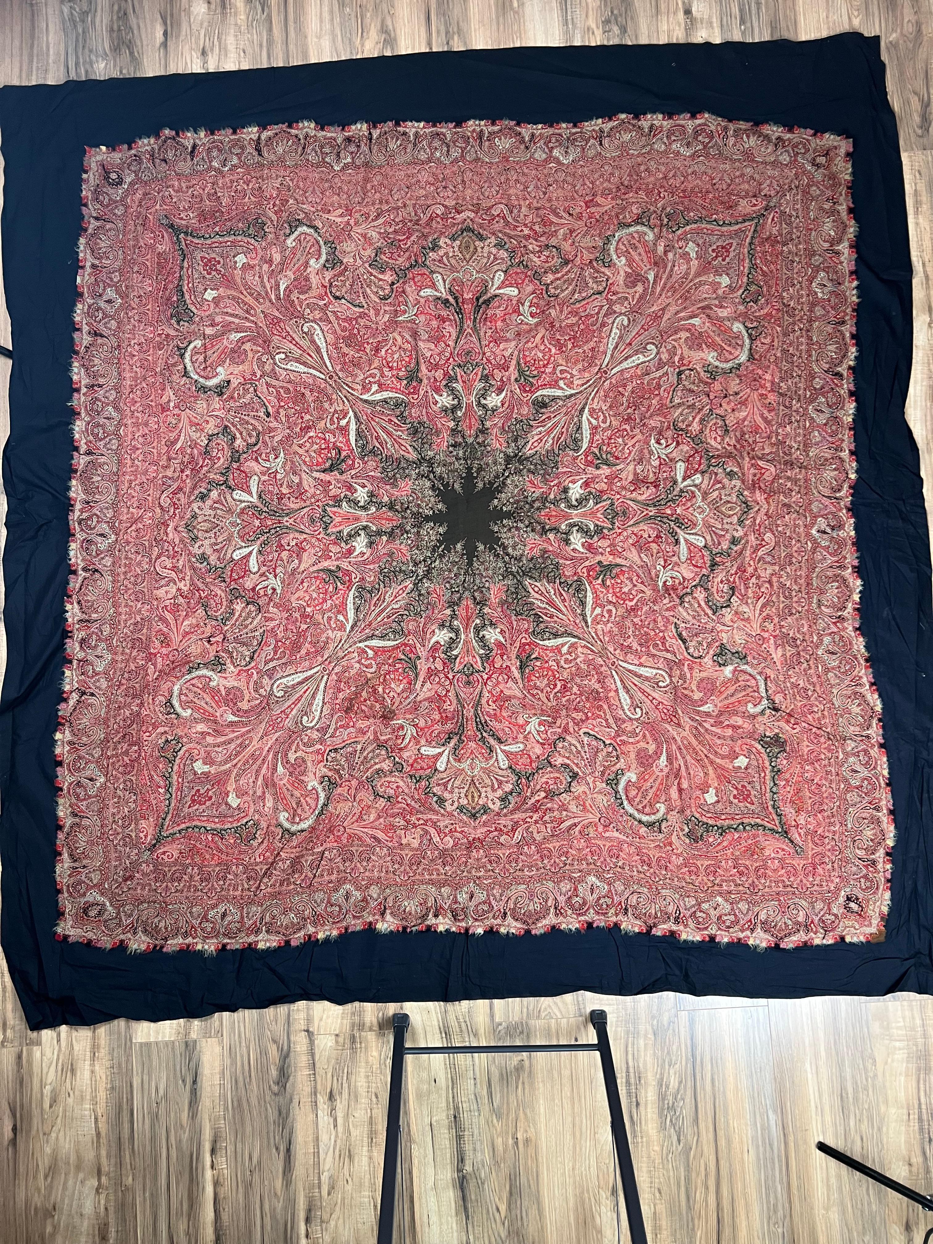 Dieser reich gewebte, antike Kani-Schal aus Kaschmir zeichnet sich durch ein kühnes zentrales Medaillon aus, von dem aus sich lebhafte Blumen- und Paisley-Formen sternförmig ausbreiten. Das Design ist in tiefen Rot-, Blau- und Goldtönen gehalten,