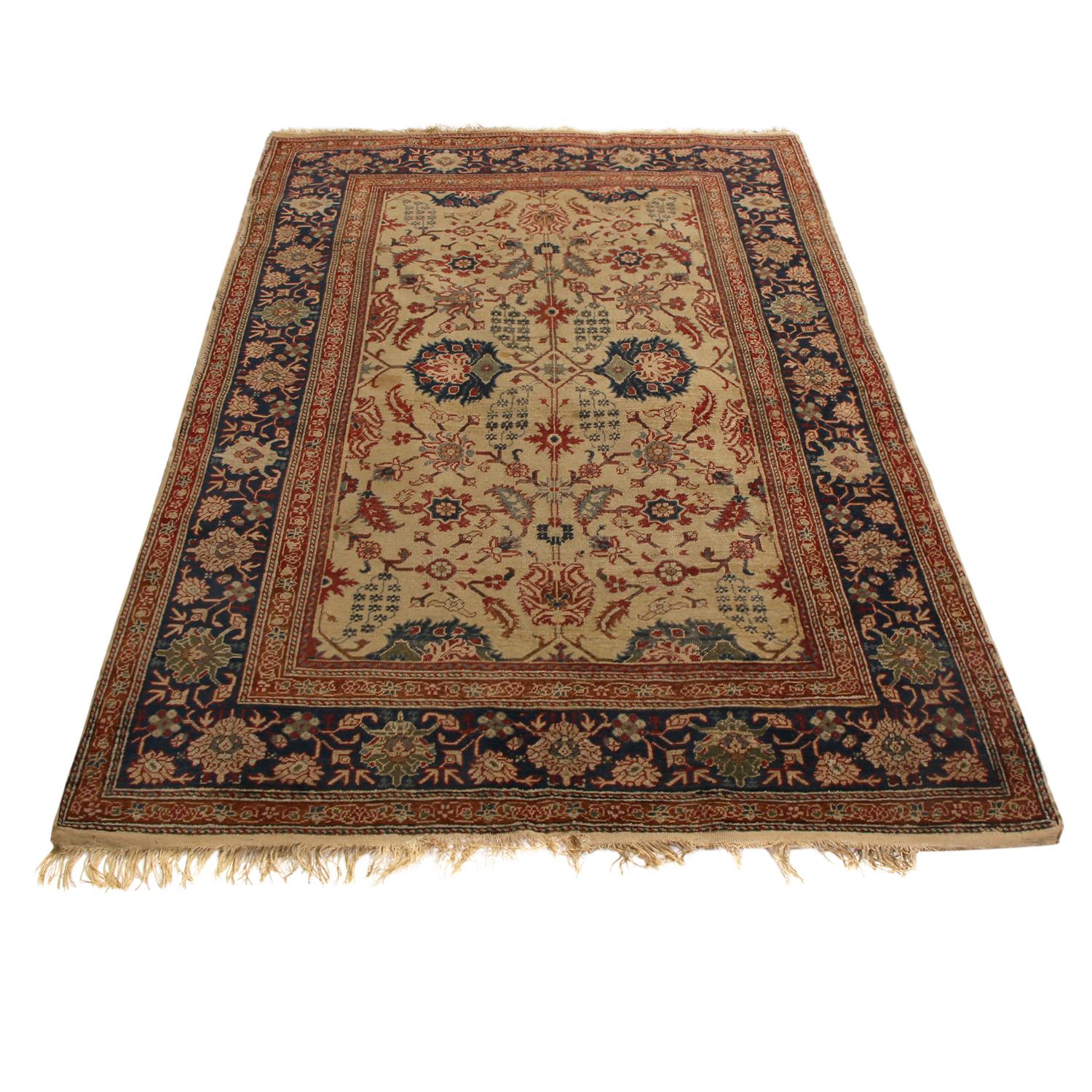 Hand knotted in high-quality wool originating from Turkey between 1890-1900, this antique Kayseri wool rug hosts a classic pairing of russet and navy blue color ways complemented by a beige field background. Enjoying pristine condition and