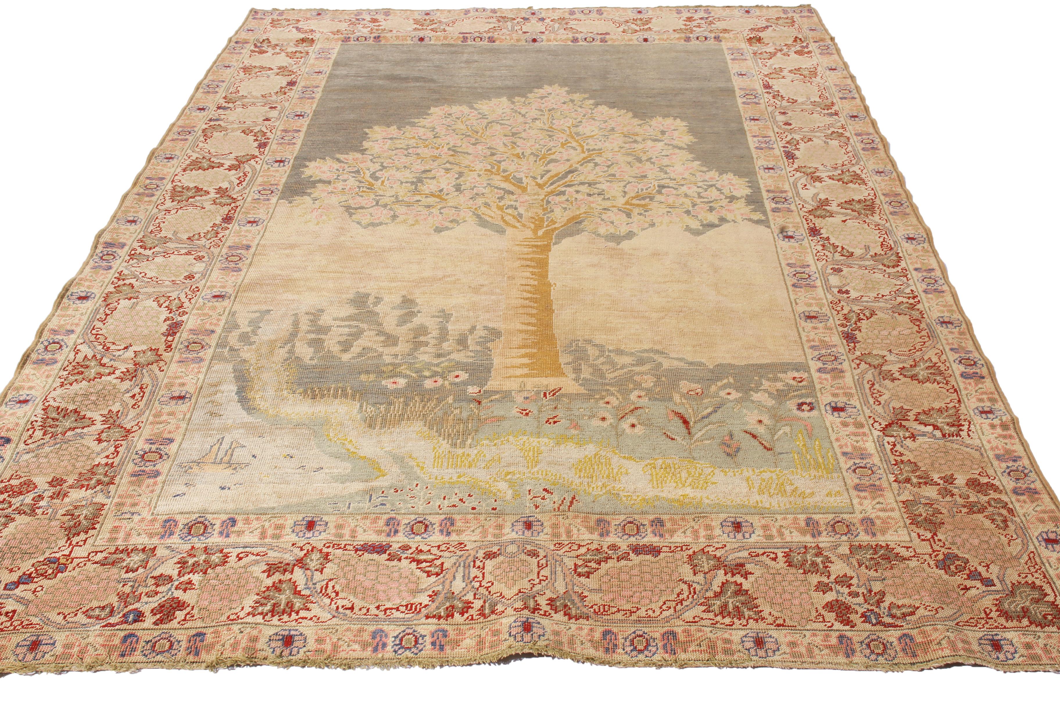 Originating from Turkey in 1910, this antique Kayseri rug enjoys a realist, one-sided field design with a variety of floral patterns in the mirrored borders. Hand knotted in durable wool pile, the nature setting depicting a lone, stylistic tree in a
