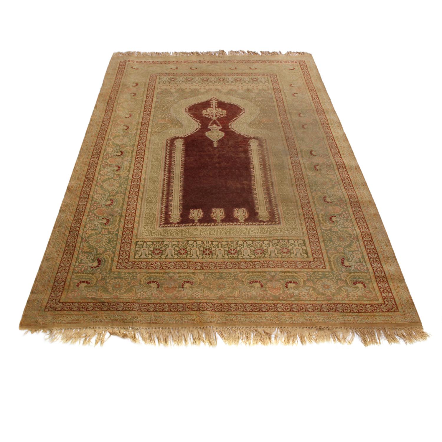 Hand knotted in high-quality wool originating from Turkey in 1870, this antique Kayseri rug enjoys an engaging, rich shade of burgundy complementing the more forgiving tea green and beige colorways, balancing the visual gravity of the central mihrab