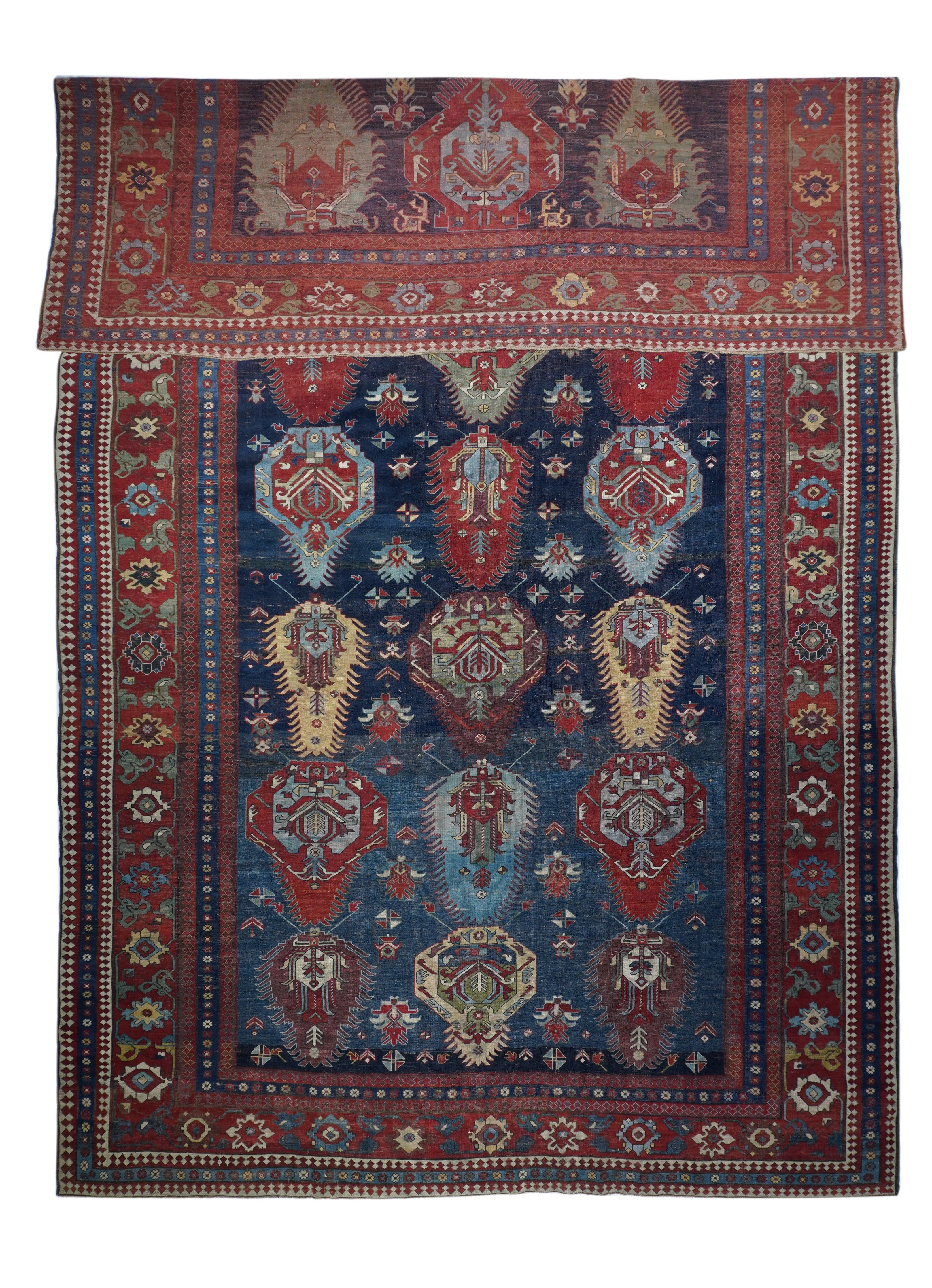 Antico Kazak/Azarbayjan  Tappeto 10'6'' x 17'8''. Un pezzo interamente in lana della zona di confine, con tre colonne di sette file di plaquette interamente o parzialmente frangiate che racchiudono palmette geometriche a petali, su un fondo blu