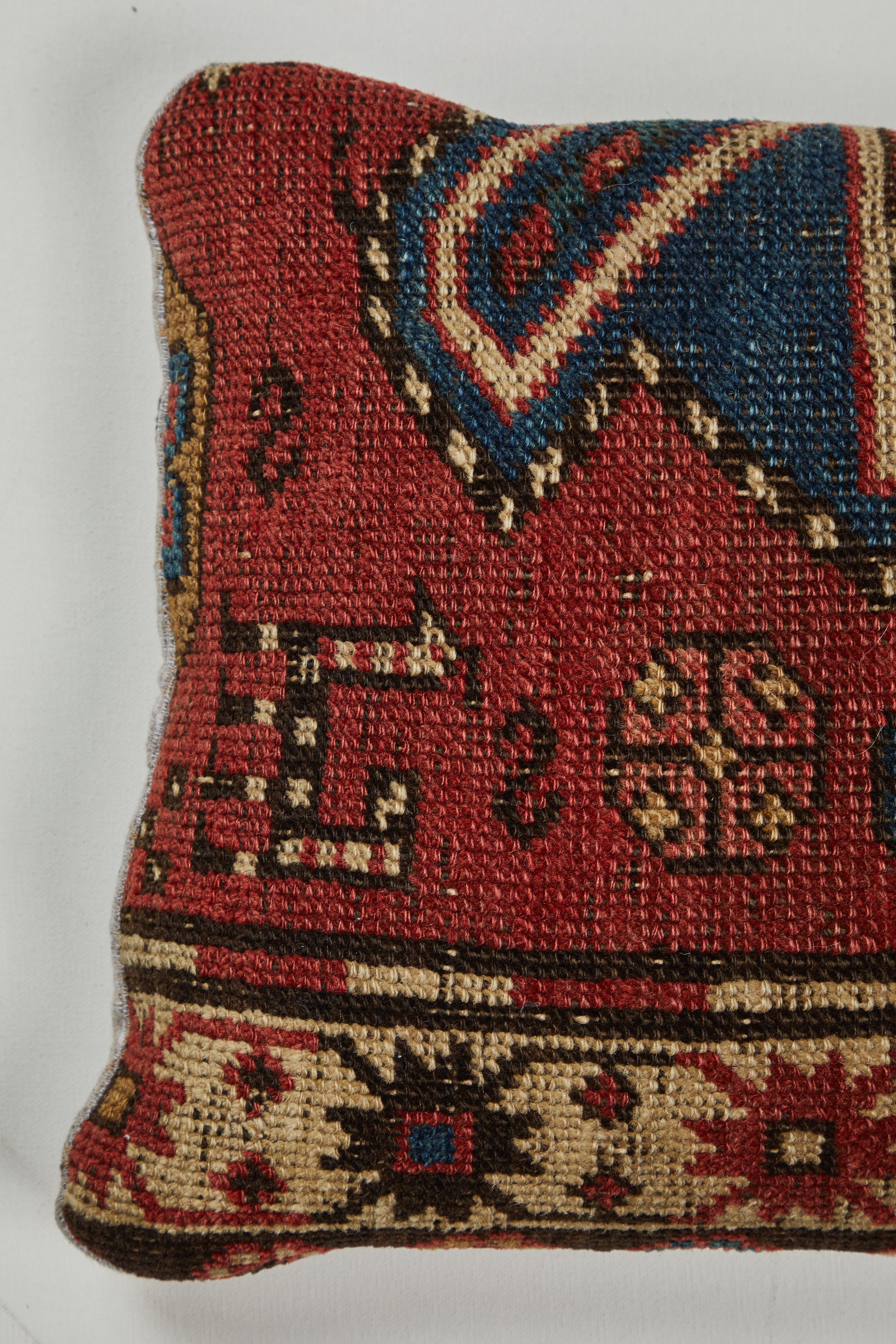 Rug fragment showing edge details including 2 fanciful striped animals. Kazak Caucasian tribal rug. Backed with handwoven Indian khadi cotton. Zipper closure across back and feather and down fill.