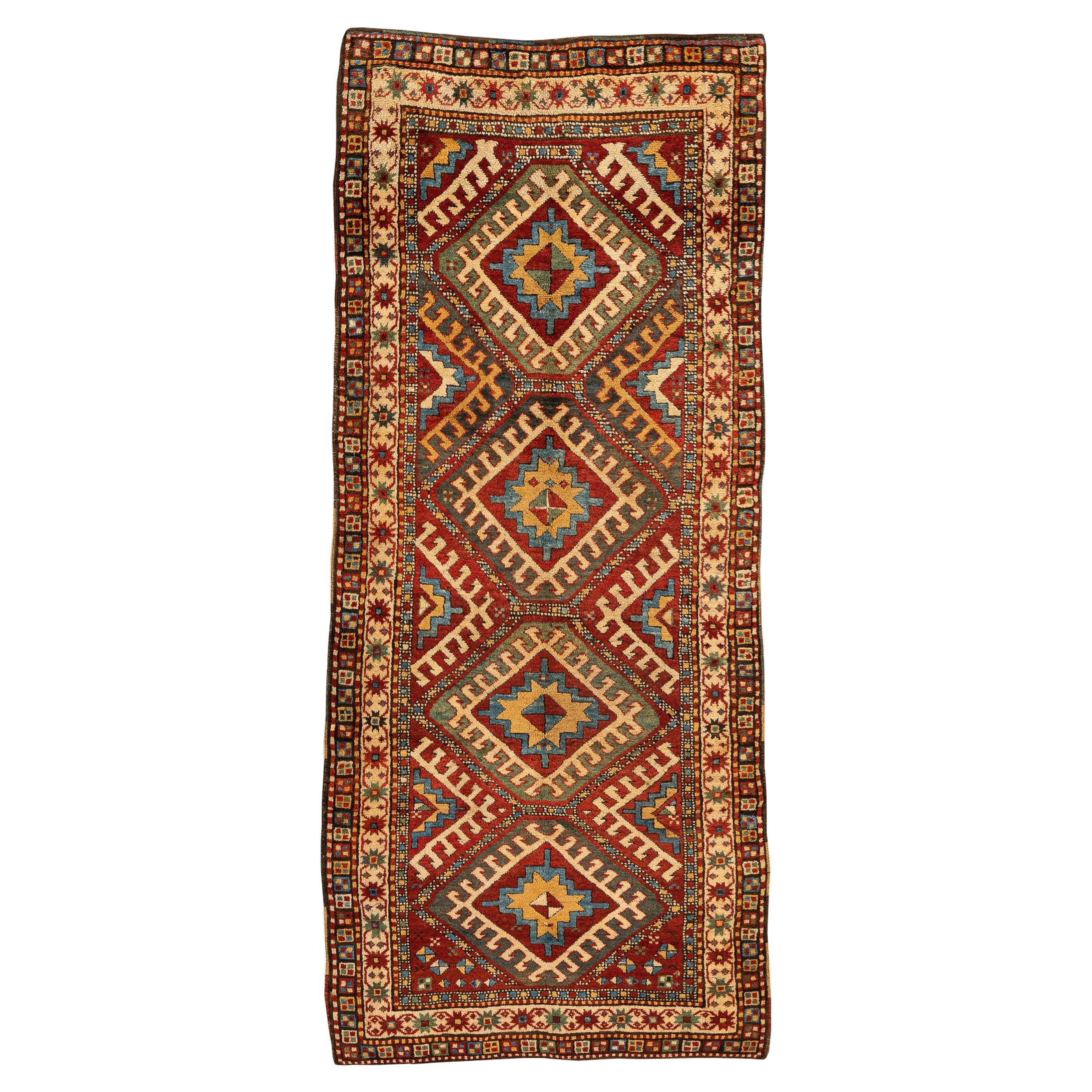 Kazak – Central Caucasus

This is a beautiful antique Kazak rug with natural dyes in vibrant tones. Four diamond-shaped medallions with hooks on their sides dominate the central field. Around the diamonds, different geometric figures fill the red