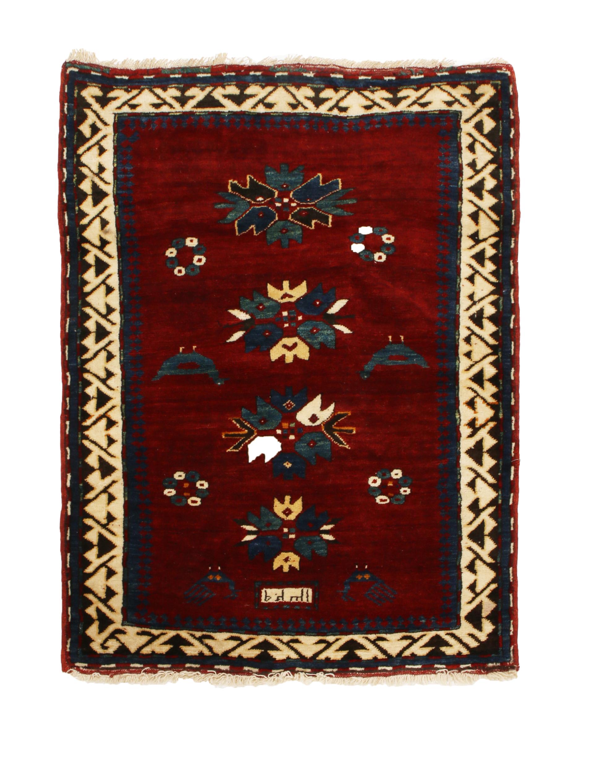 Hailing from Russia between 1890-1900, this hand knotted antique Kazak wool rug is a signature piece employing traditional tribal colorways in a crimson red background with beige and royal blue floral motifs. It is especially uncommon to see this