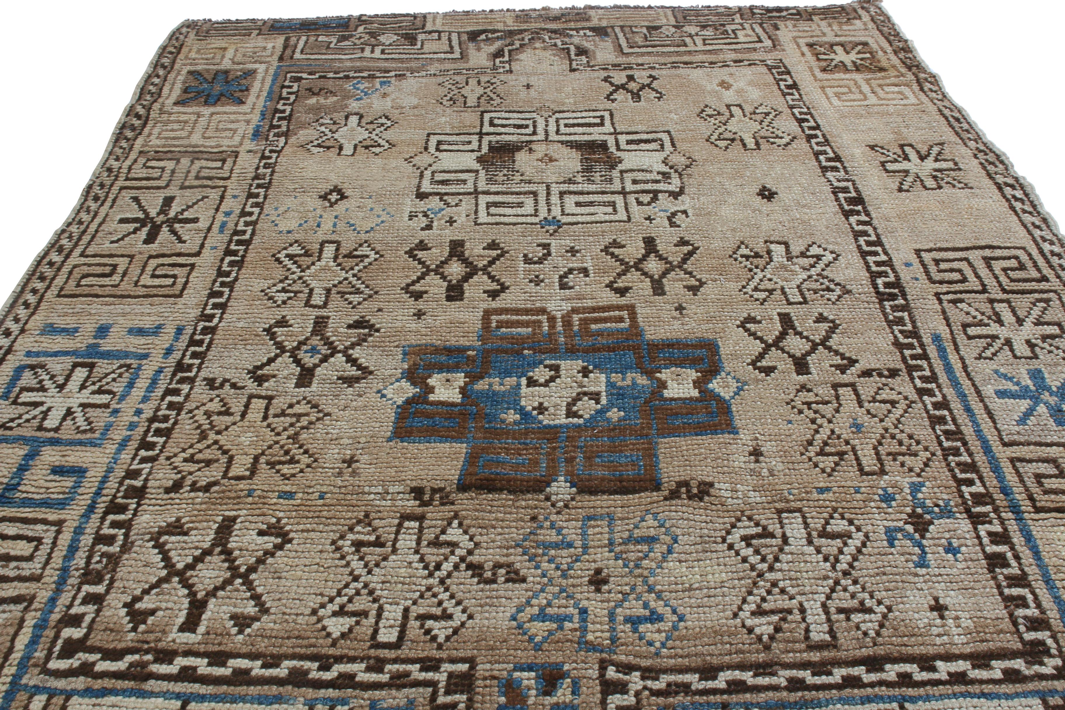 Originating from Russia in 1920, this antique traditional Kazak wool rug enjoys an uncommon colorway pagination to its Dual medallion-style field design. Hand knotted in high quality wool with rustic beige, luminous blue, and rich brown colorways, a