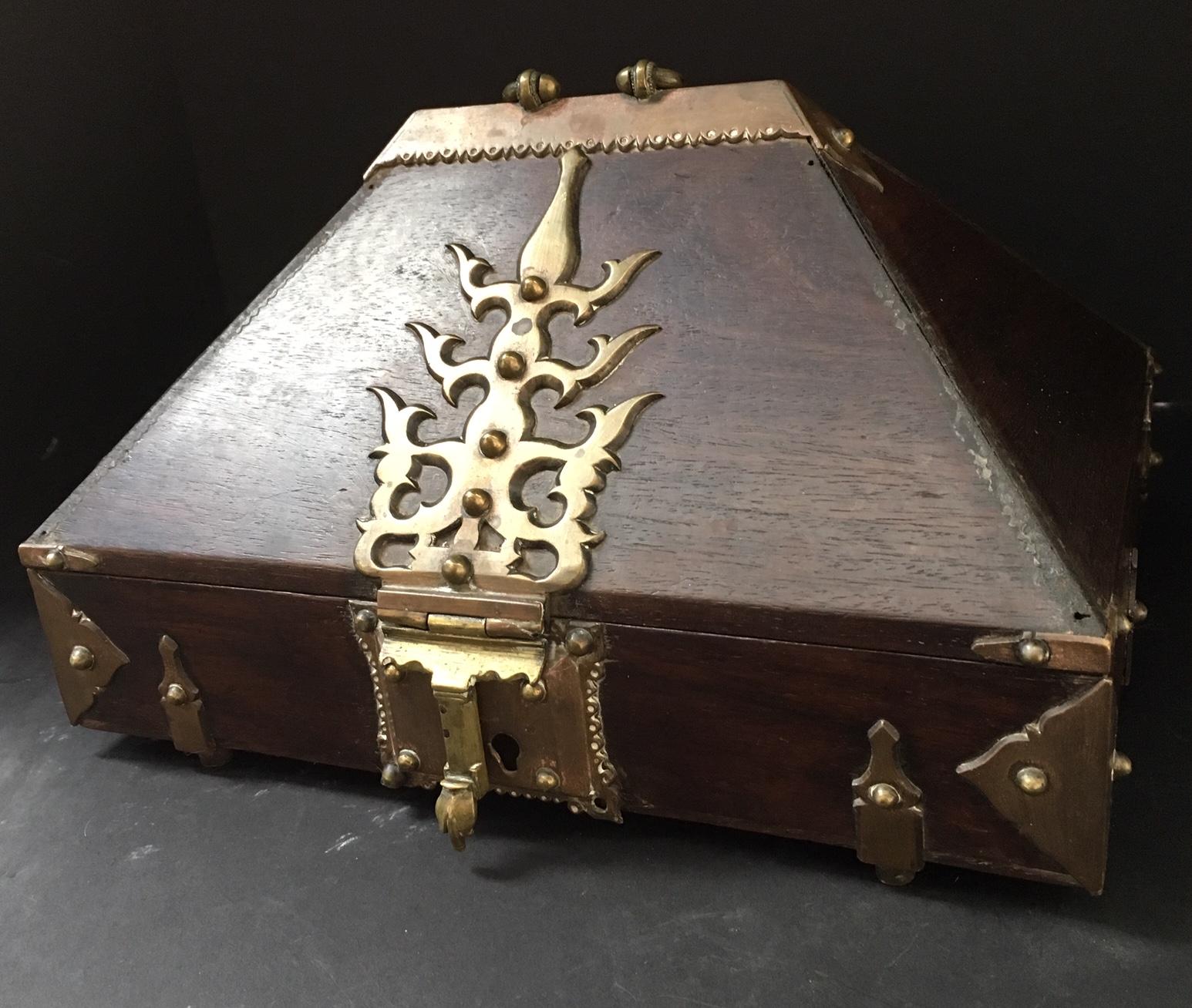 This is an original and decorative 19th or early 20th century Indian jewelry or dowry chest. It is in pyramidal shape with fanciful brass hardware. The chosen wood is mahogany, which gives this box a very rich look. The domed lid is hinged to the