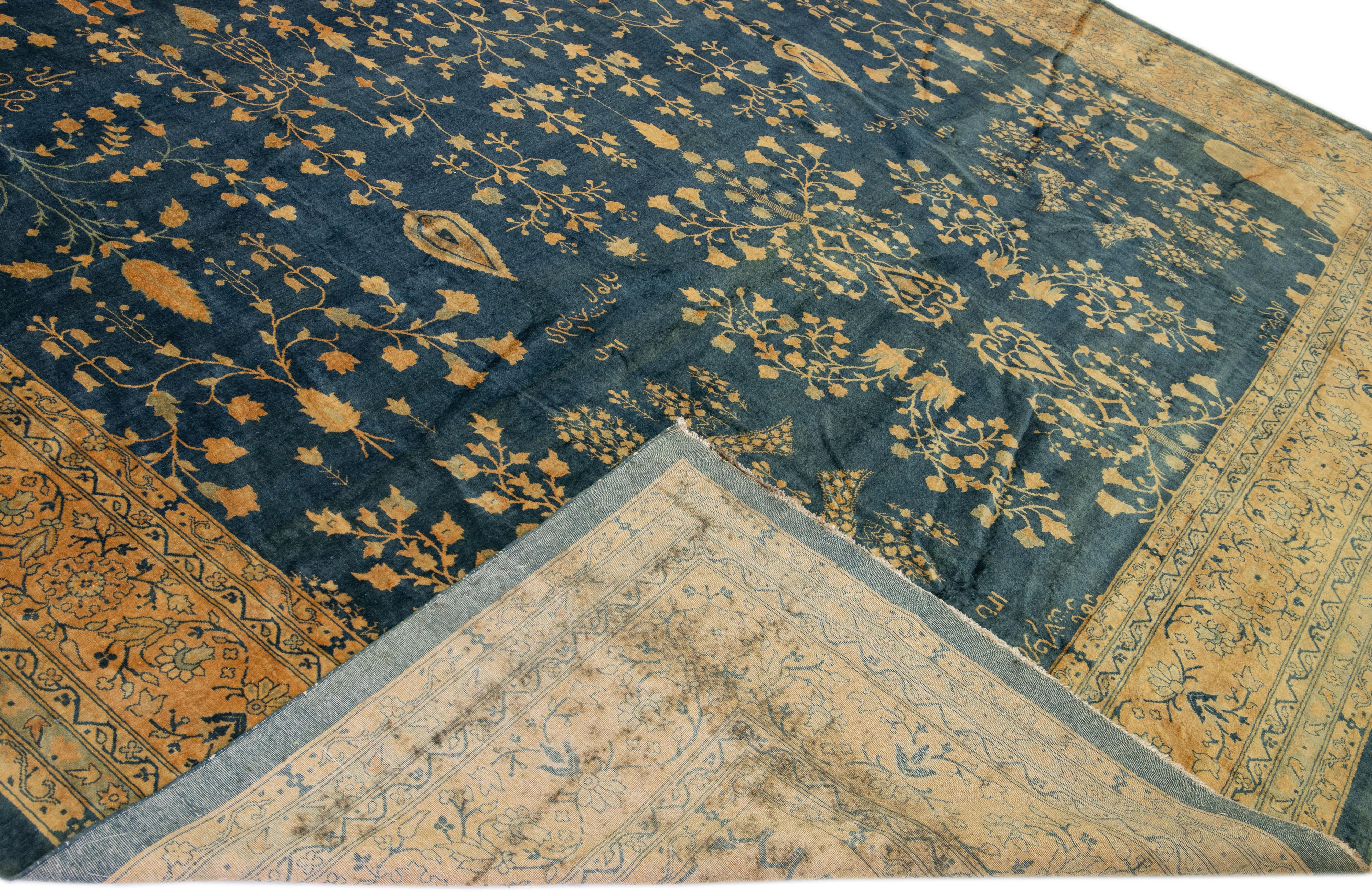 Beautiful antique Kerman hand-knotted wool rug with a navy blue field. This Persian rug has a beige frame and tan accents in a gorgeous all-over rosette pattern design.

This rug measures: 13' x 23'6