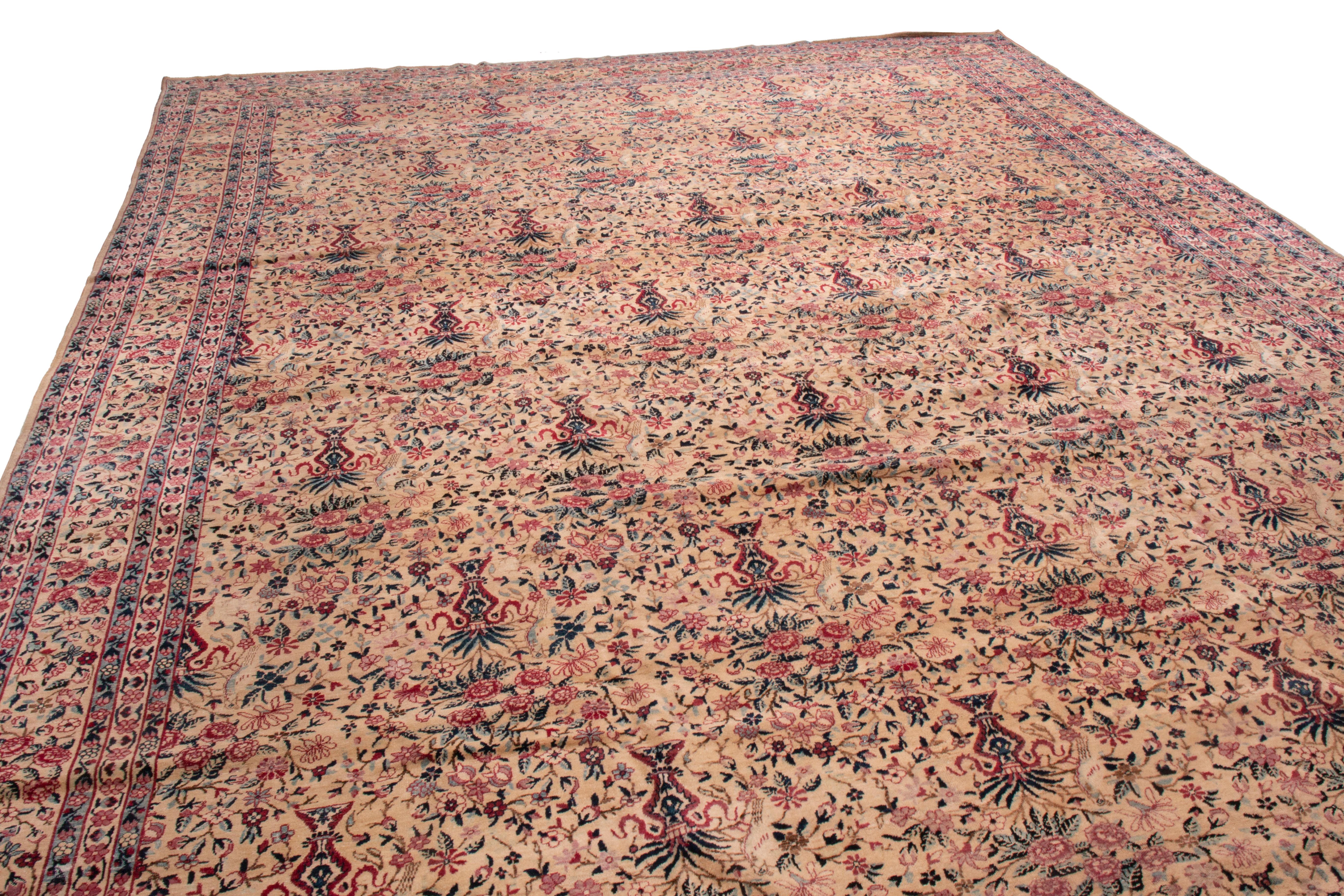 Dieser antike Lavar-Teppich aus Kerman ist von der viktorianischen Ära beeinflusst. Das All-Over-Feldmuster zeigt traditionelle Blumenvasen und Vögel in Violett, Rot und Grün, wobei die Weinranken in der Bordüre dunklere Violett-Töne isolieren. Es