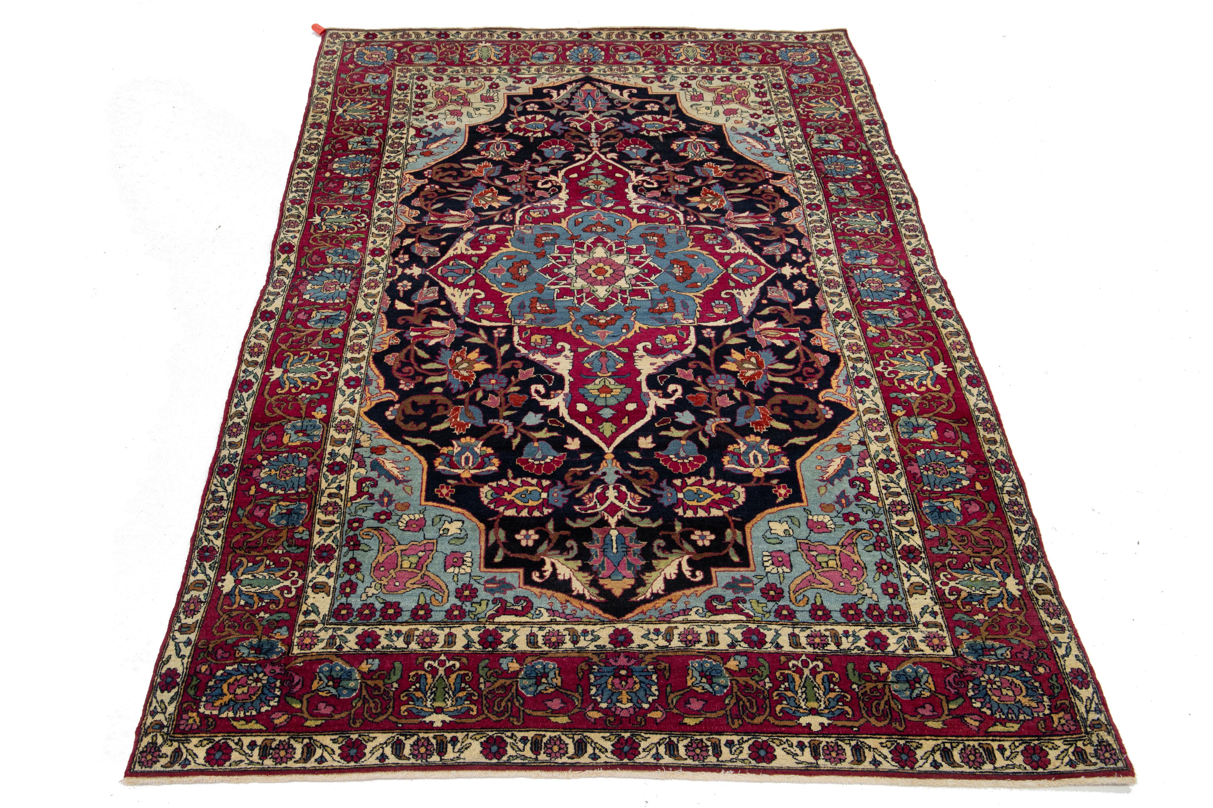 This hand-knotted wool rug, an impressive antique from the 1920s, showcases a vibrant floral design in various colors that beautifully contrast with its deep blue background.

This rug measures 4'4