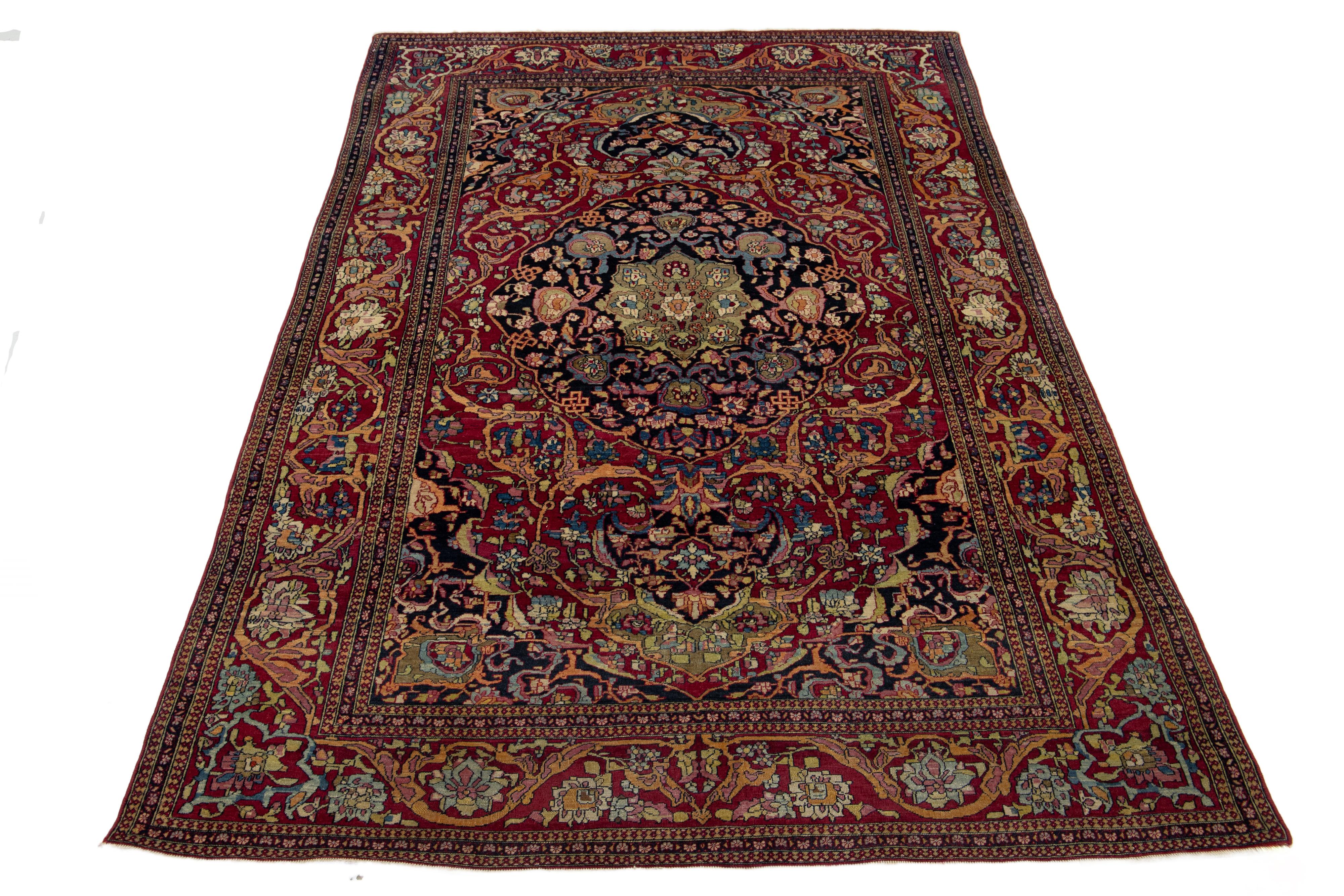 Ce tapis en laine noué à la main est une remarquable antiquité des années 1920. Il est orné d'un vibrant motif floral aux couleurs variées qui contrastent magnifiquement avec le bleu profond et le rouge du fond.

Ce tapis mesure 4'7