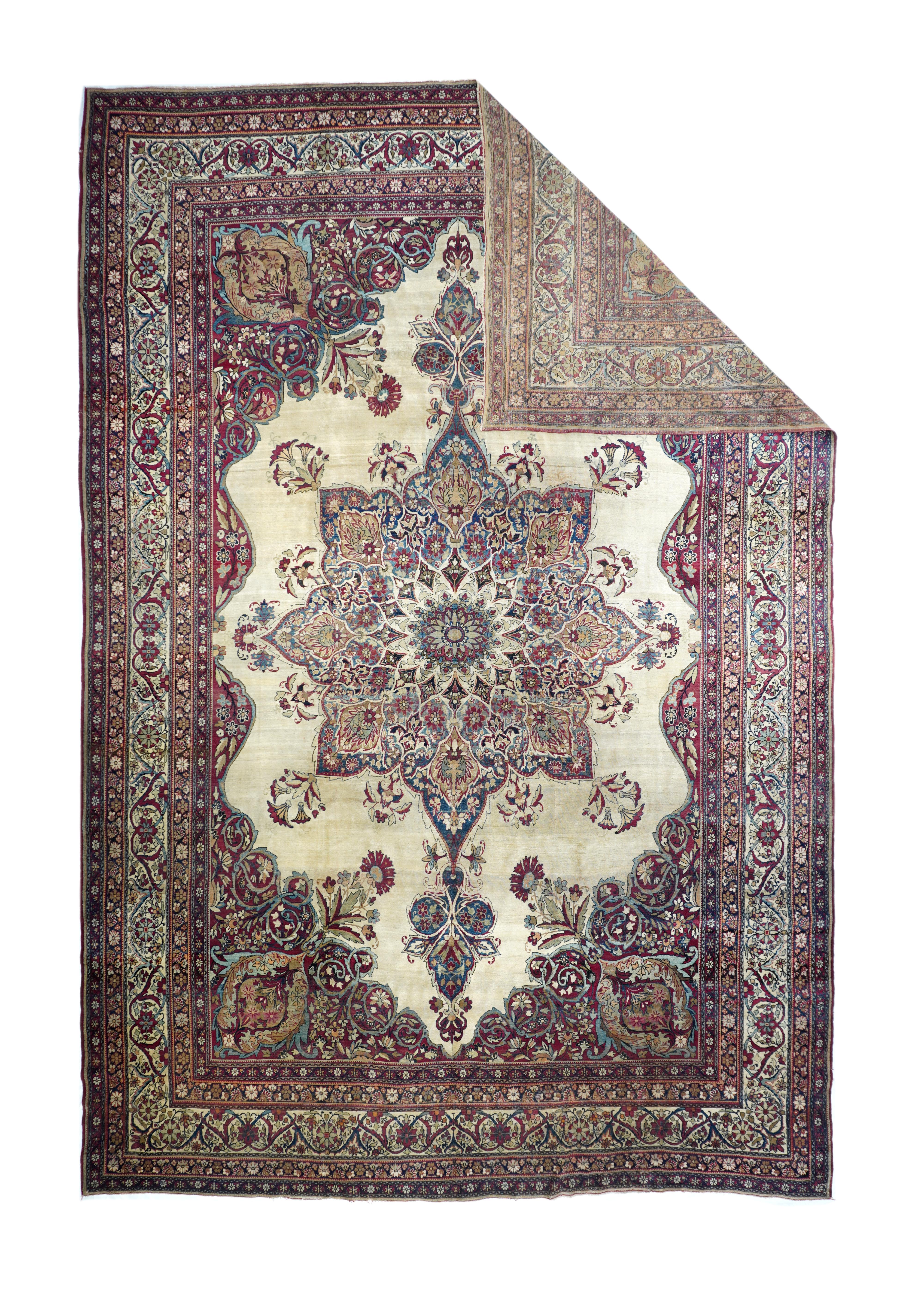 This finely woven SE Persian city carpet shows a shaped and indented ecxru-beige semi-open field centred by an octogramme filigree medallion with eight floral pendants and a 16 point sub-medallion. Cochineal read volute corners with emerging