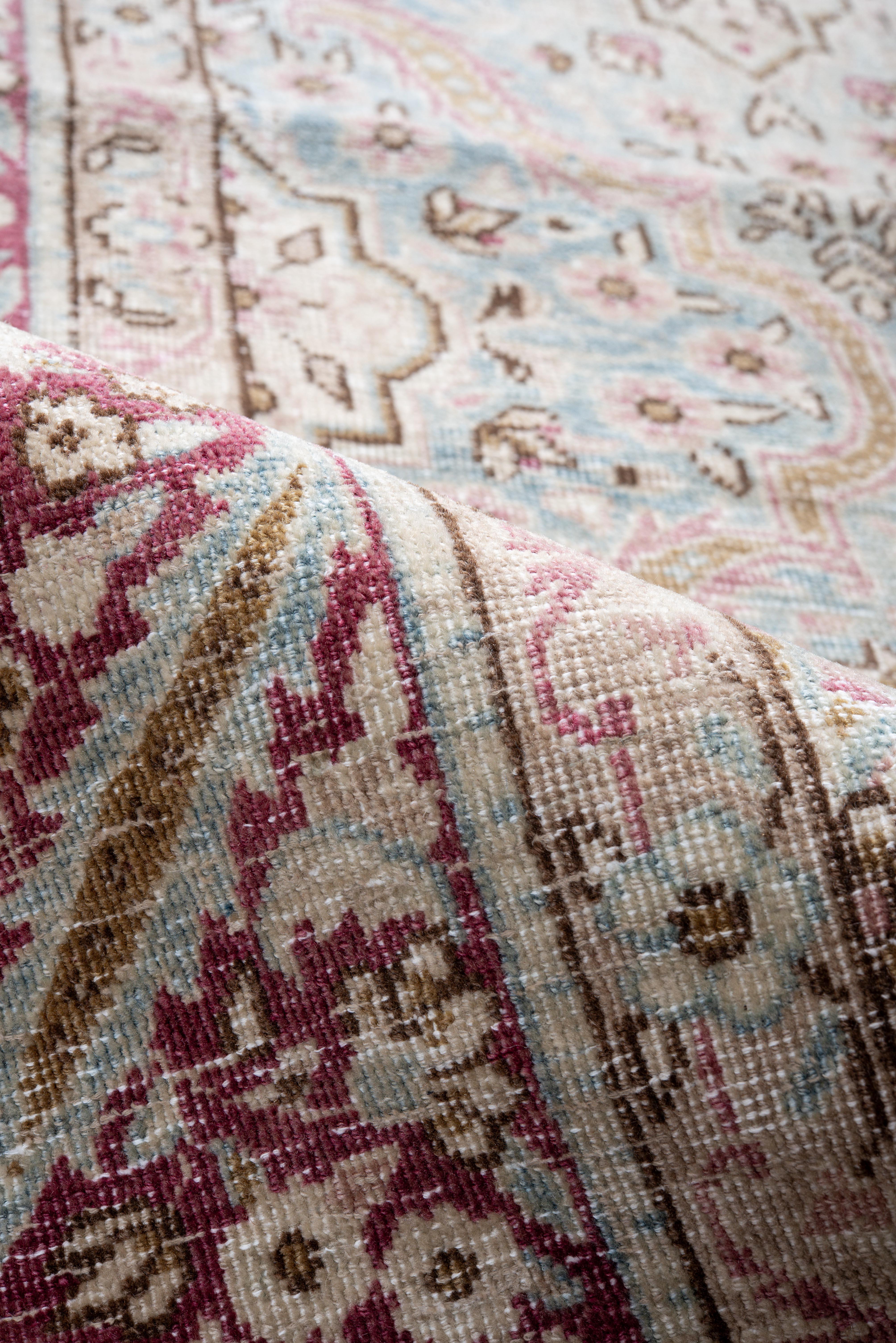 Ce tapis ancien de Kerman présente un treillis raffiné de médaillons floraux et de vignes enroulées sur un champ bleu ciel délavé, accentué par des tons délicats de rose, d'ivoire et de cacao. Le motif est gracieusement orchestré avec des rosettes