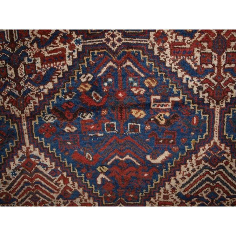 Ein klassisches Beispiel für einen Khamseh-Vogel-Teppich. Sechs elfenbeinfarbene, miteinander verbundene Medaillons auf einem indigoblauen Feld mit Vögeln und Tieren. Eine prächtige Bordüre umrahmt den Teppich. Der Teppich hat eine sehr nützliche,