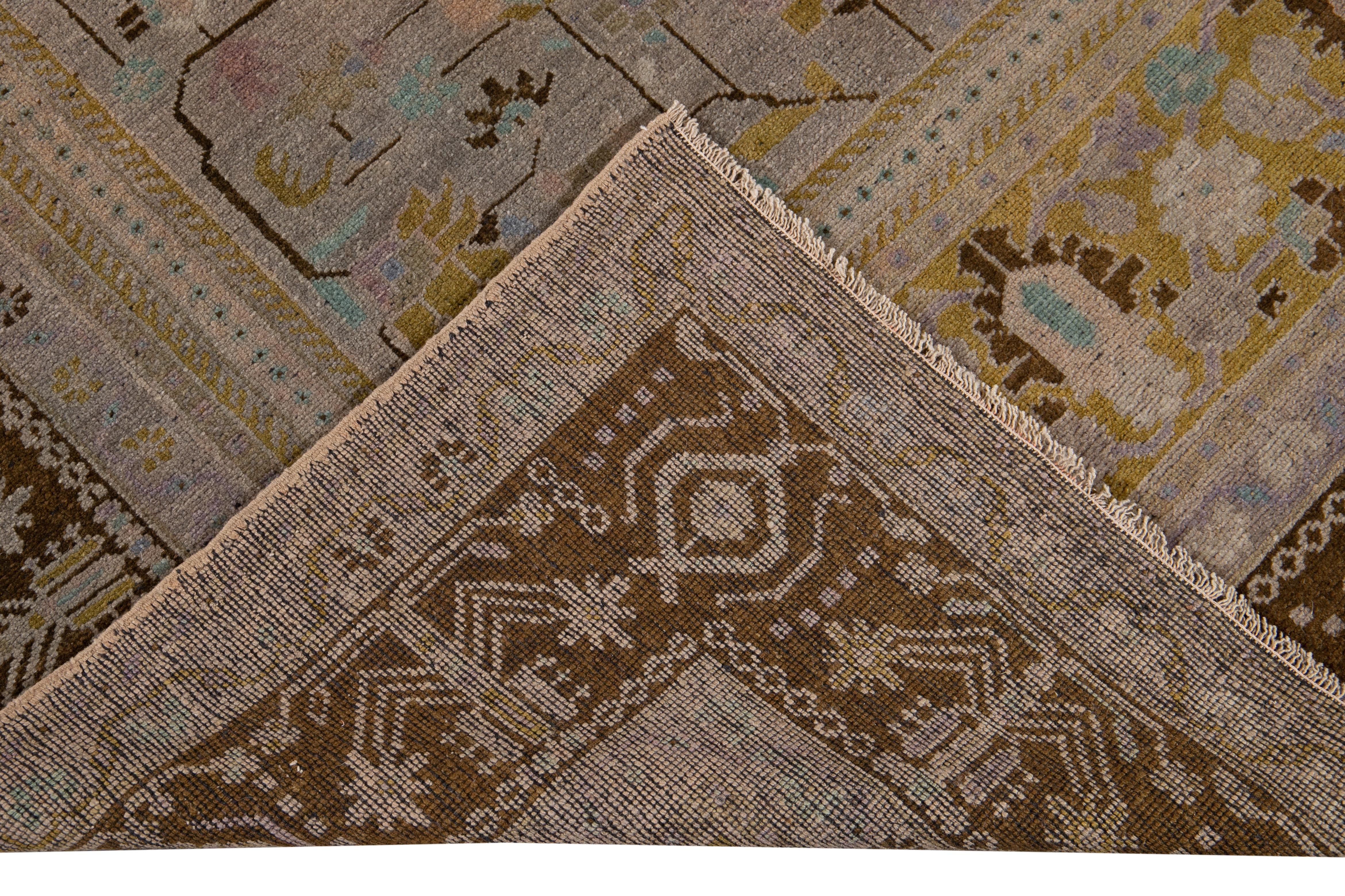 Beautiful antique Khotan hand-knotted wool rug with a Tan field. This Khotan rug has a brown designed frame with Lila, blue, and brown accents in an all-over geometric medallion floral design. 

This rug measures 7'5