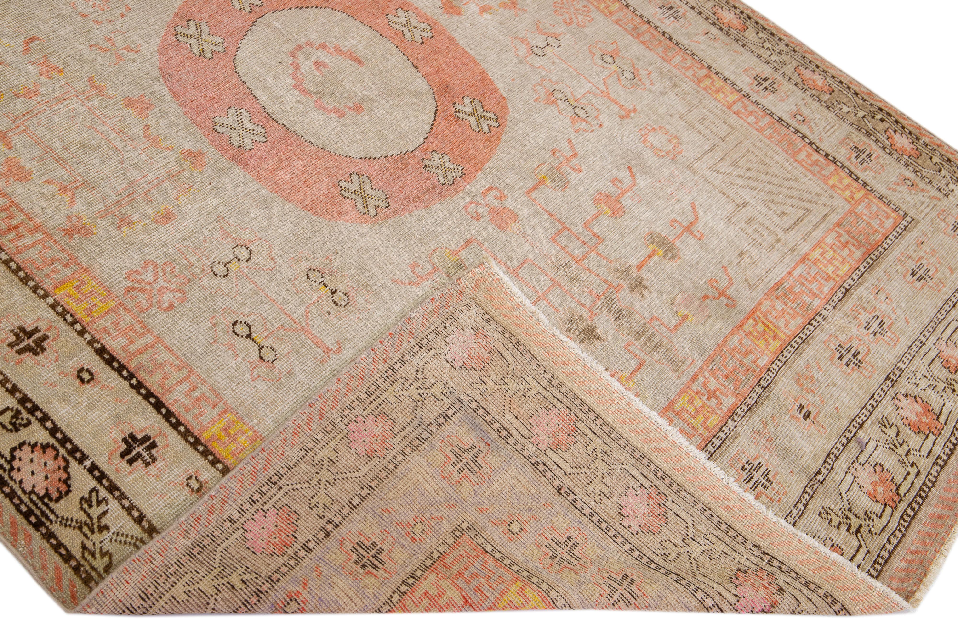 Beautiful antique Khotan hand-knotted wool rug with a beige color field. This Khotan rug has brown, yellow, and peach accents in a geometric multi-medallion design. 

This rug measures 5'6