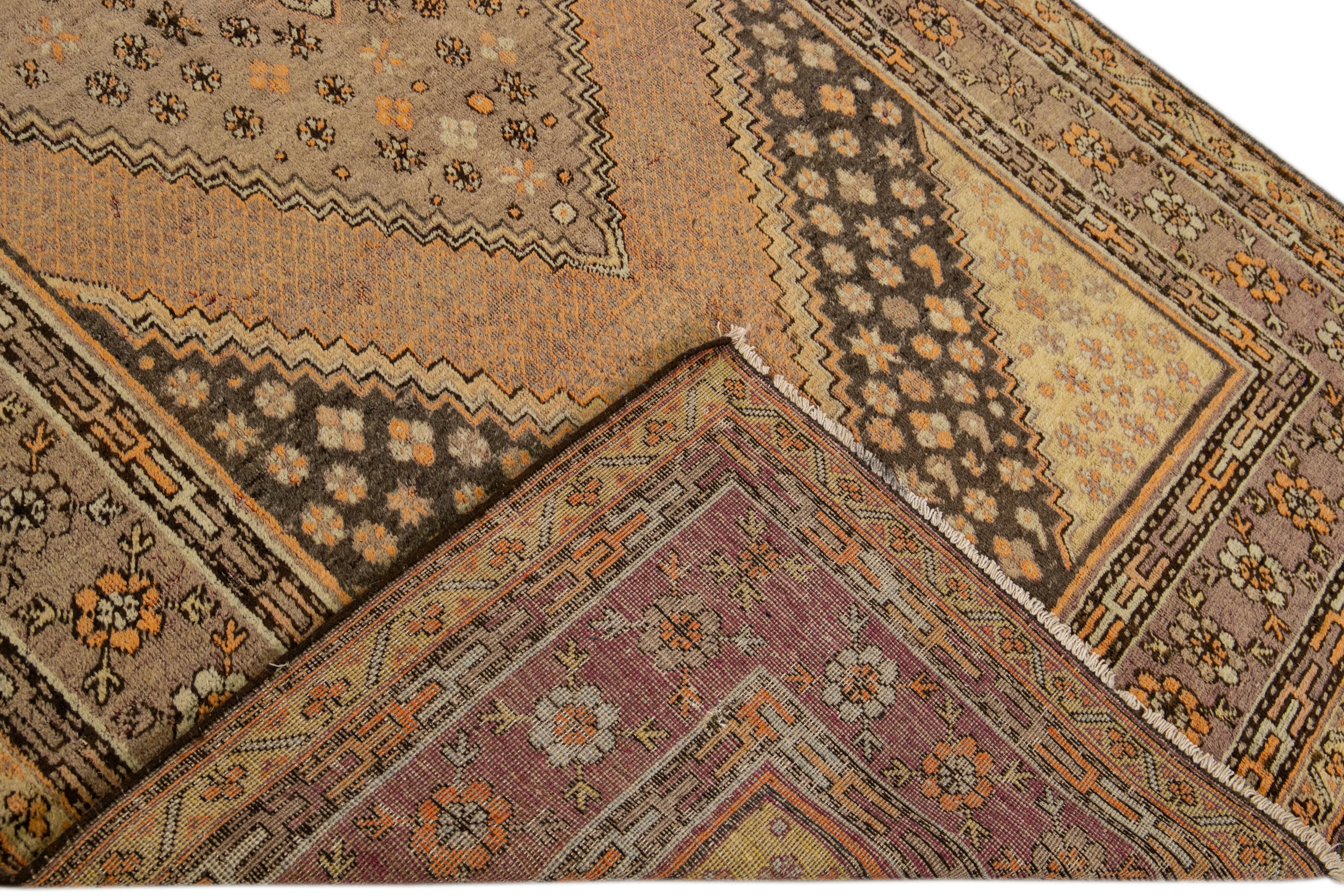 Beautiful antique Khotan hand-knotted wool rug with a tan field. This Khotan rug has a brown and orange accent in an all-over medallion floral design. 

This rug measures 5'7
