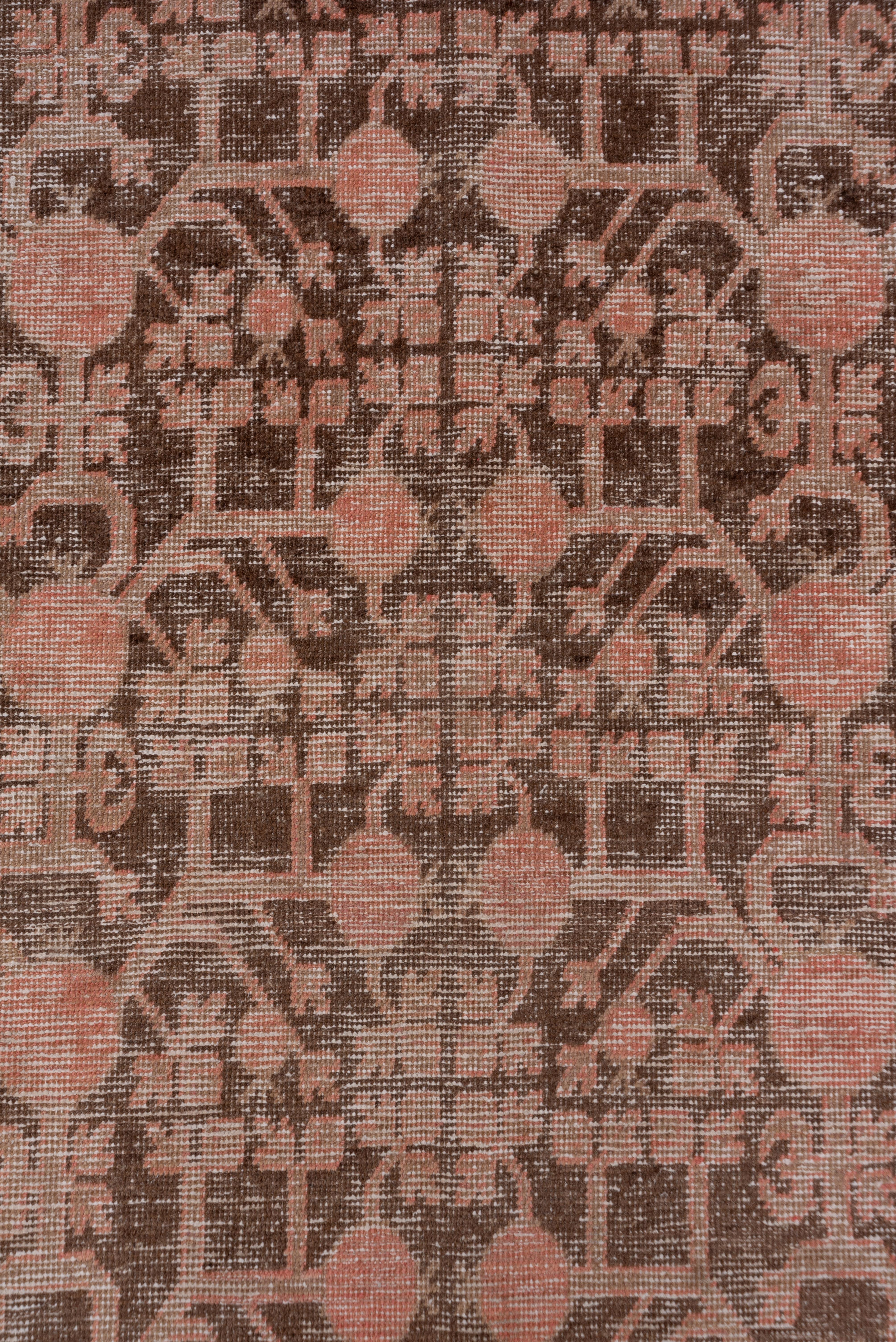 The brownish-red field displays two double-ended pomegranate trees springing from vases at each end of the field. in a popular Khotanese Xinjiang Province carpet design. The double border is accented in a similar sienna brown for the simplified