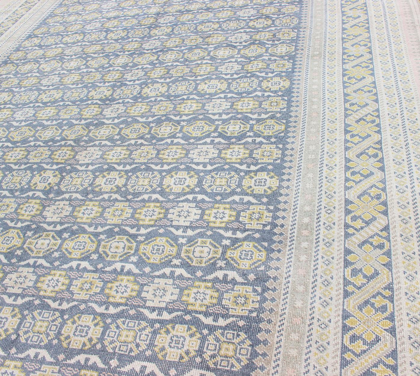 Alfombra antigua Khotan en tonos azules con acentos grises, l. rosas y amarillos siglo XX en venta