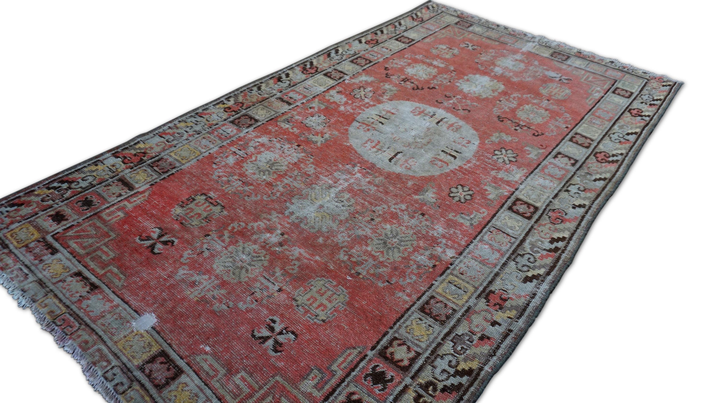Ce tapis ancien en laine nouée à la main, datant du début du 20e siècle, incarne magnifiquement l'art traditionnel et présente un charme élégant et ancien. Doté d'un champ rouge corail délavé et d'un motif central de style médaillon en crème et