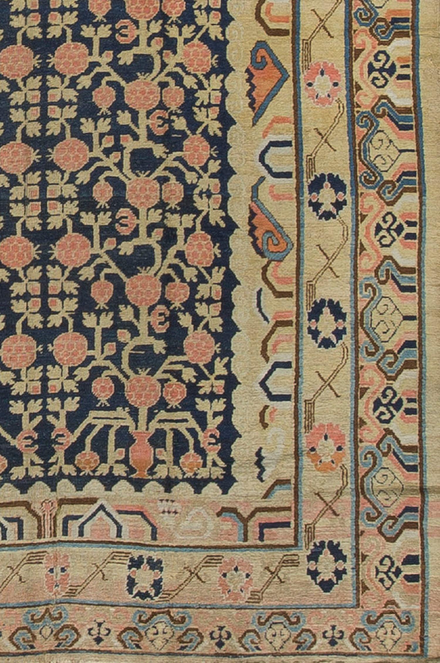 Un merveilleux tapis antique Khotan avec un fond bleu marine rempli de motifs de grenades et entouré de trois bordures pour créer un look vraiment spectaculaire. Le motif de la grenade est un symbole de fertilité dans les tapis orientaux.
 