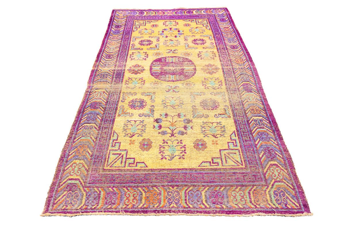 Dieser antike Seidenteppich aus Khotan ist ein prächtiges Beispiel für ostturkestanische Handwerkskunst und zeigt eine Verschmelzung kultureller Designs, die Elemente aus China, der Türkei und der Mongolei vereinen. Der Teppich hat ein sattes
