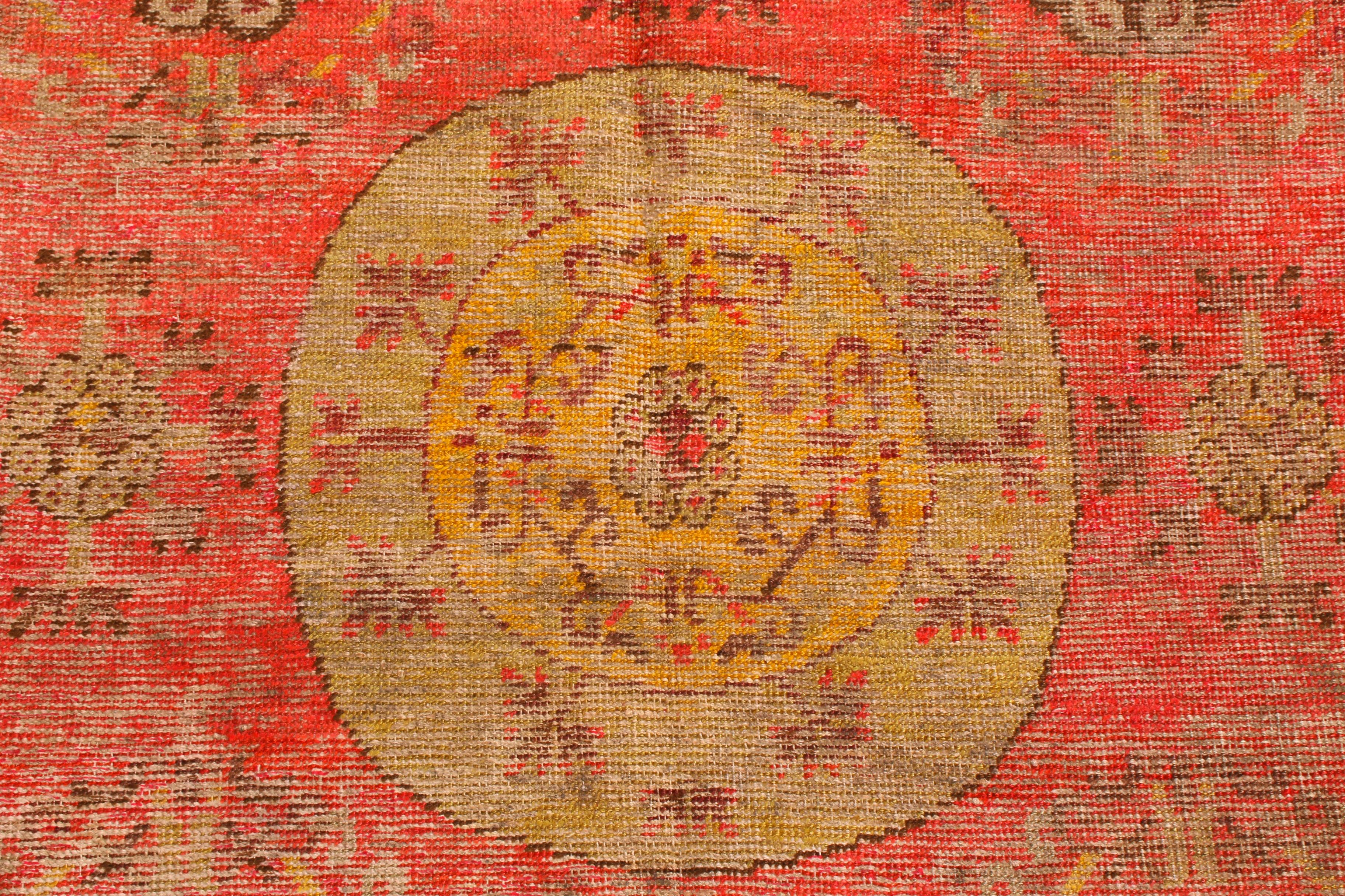 Originating from East Turkestan in the 1920s, this antique traditional Khotan rug from Rug & Kilim has a distinct medallion-style field design surrounded by key eastern symbolism. As Khotan was a Buddhist kingdom, this rug employs symbolic