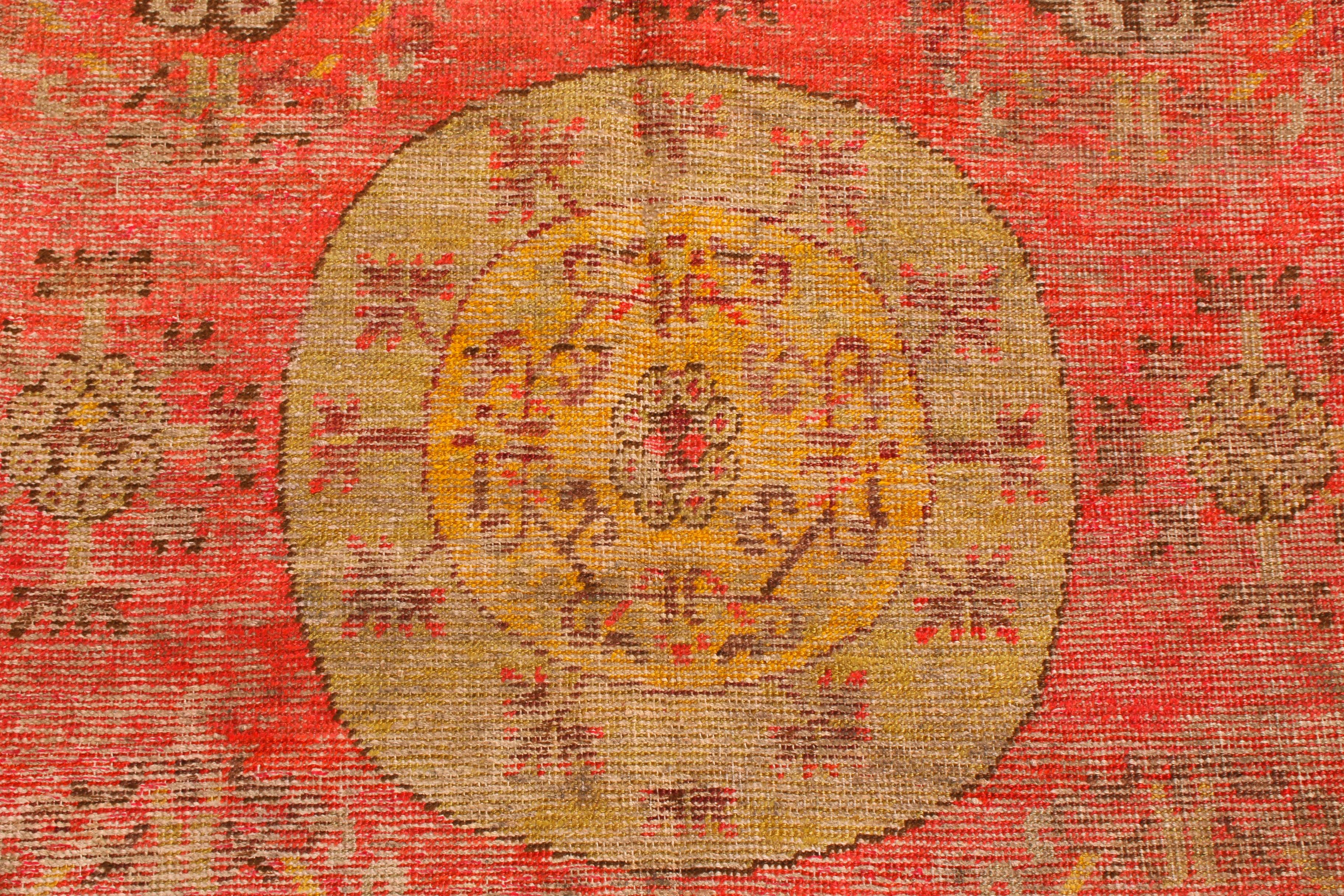 Originaria del Turquestán Oriental en la década de 1920, esta antigua alfombra tradicional Khotan de Rug & Kilim tiene un distintivo diseño de campo estilo medallón rodeado de simbología oriental clave. Como Khotan era un reino budista, esta