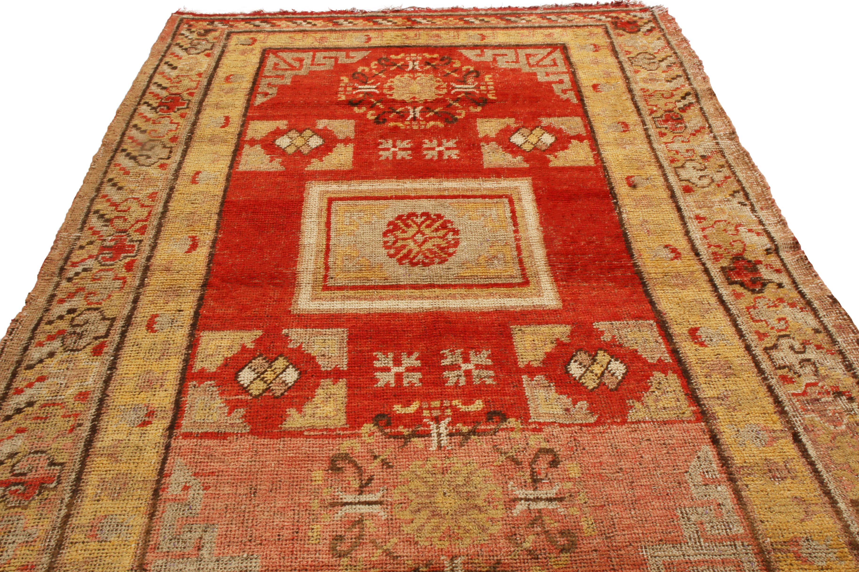 Originating from East Turkestan in 1920, this antique transitional Khotan wool rug features a distinct field design with rich and varied colors repeating throughout the piece. Hand knotted in high quality wool, the tangerine background is uniquely