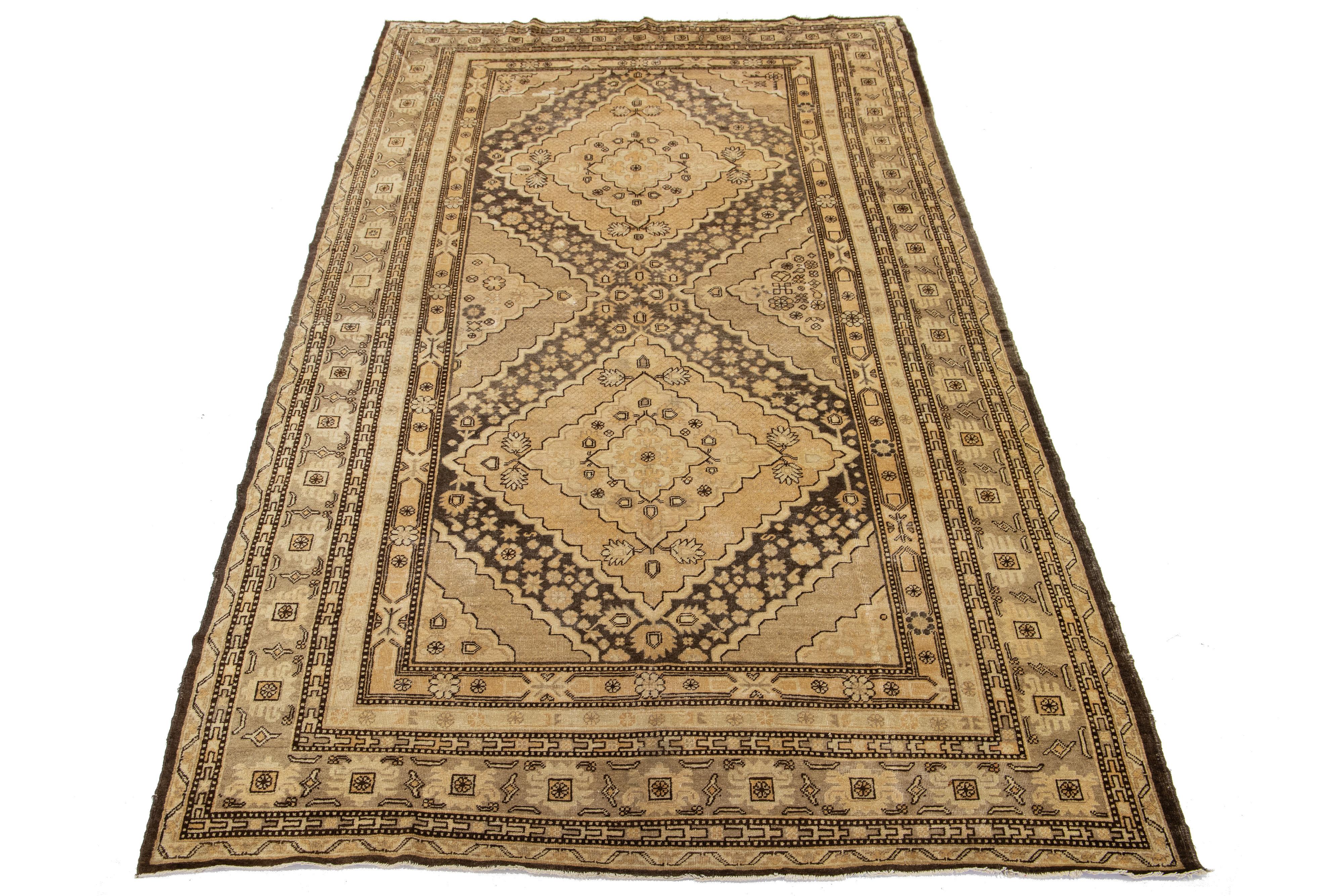 Magnifique tapis ancien en laine Khotan noué à la main avec un champ de couleur beige. Ce Khotan présente des accents bruns et beiges dans un magnifique motif médaillon.

Ce chemin de table mesure 6'9'' x 12'10