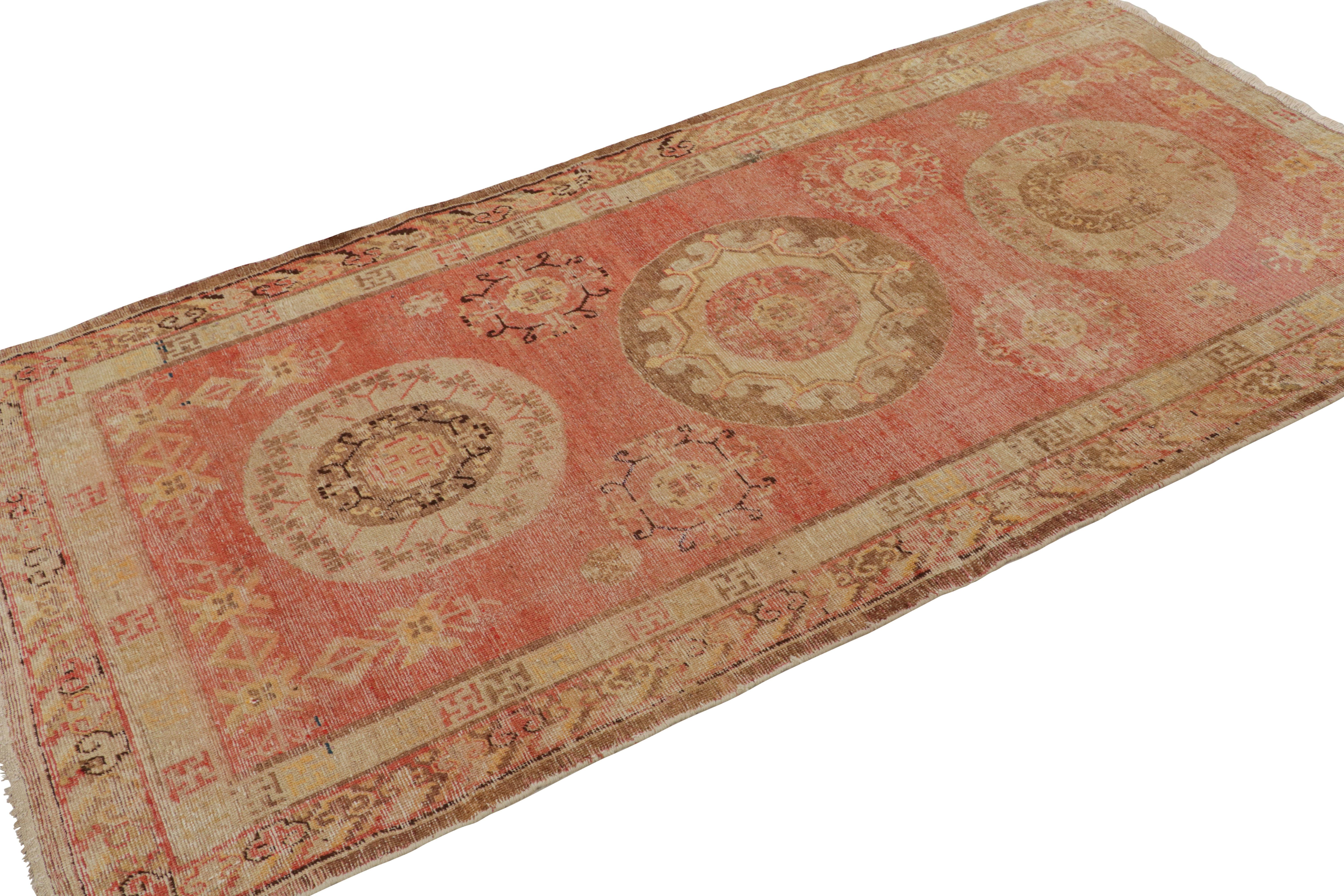 Hand knotted in high-quality wool from East Turkestan between 1910-1920, this antique Khotan rug hosts a rich variation of ornate symbols and borders, including a mirrored medallion field design enfolded with cloud band and peace symbol borders.