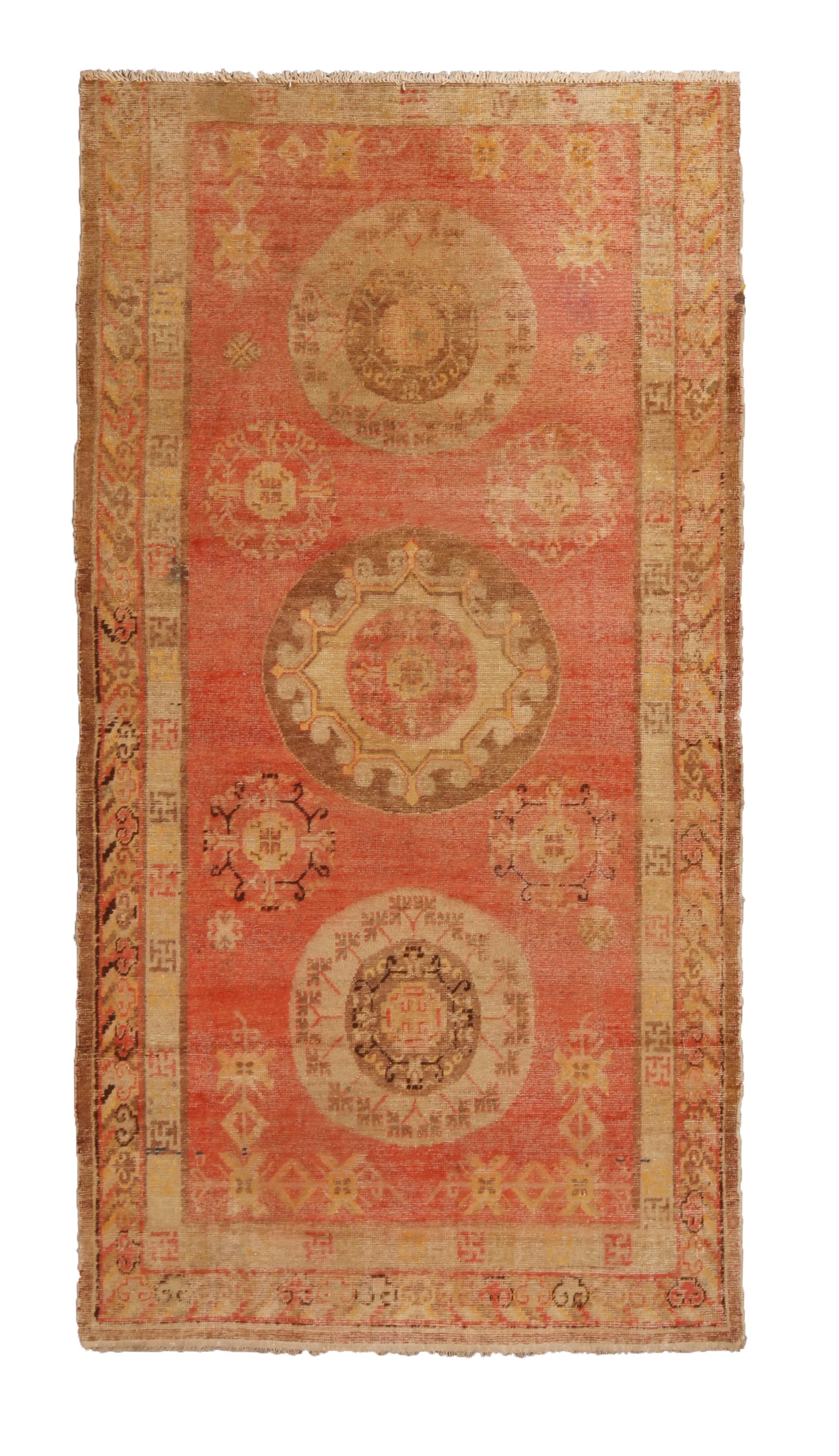Hand knotted in high-quality wool from East Turkestan between 1910-1920, this antique Khotan rug hosts a rich variation of ornate symbols and borders, including a mirrored medallion field design enfolded with cloud band and peace symbol borders.