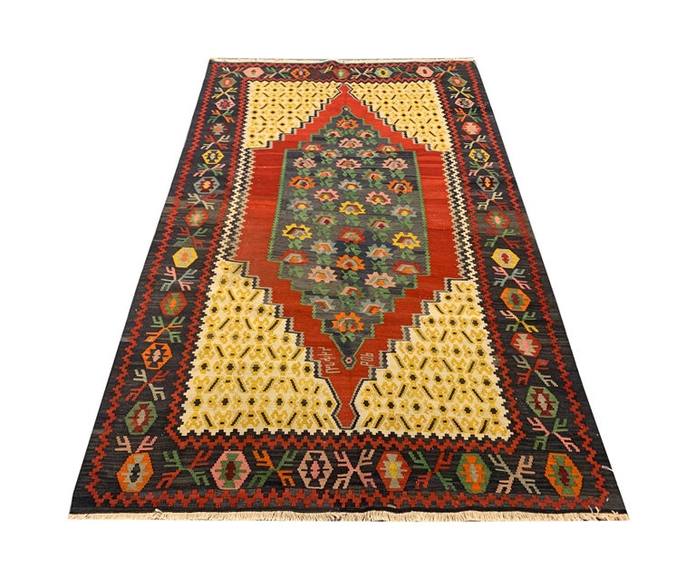 This elegant antique Caucasian Karabagh kilim rug features a vibrant colour palette and sleek design. Red, yellow and green make up the primary colours in this piece. Floral motifs mix with geometric patterns to create this beautiful eye-catching