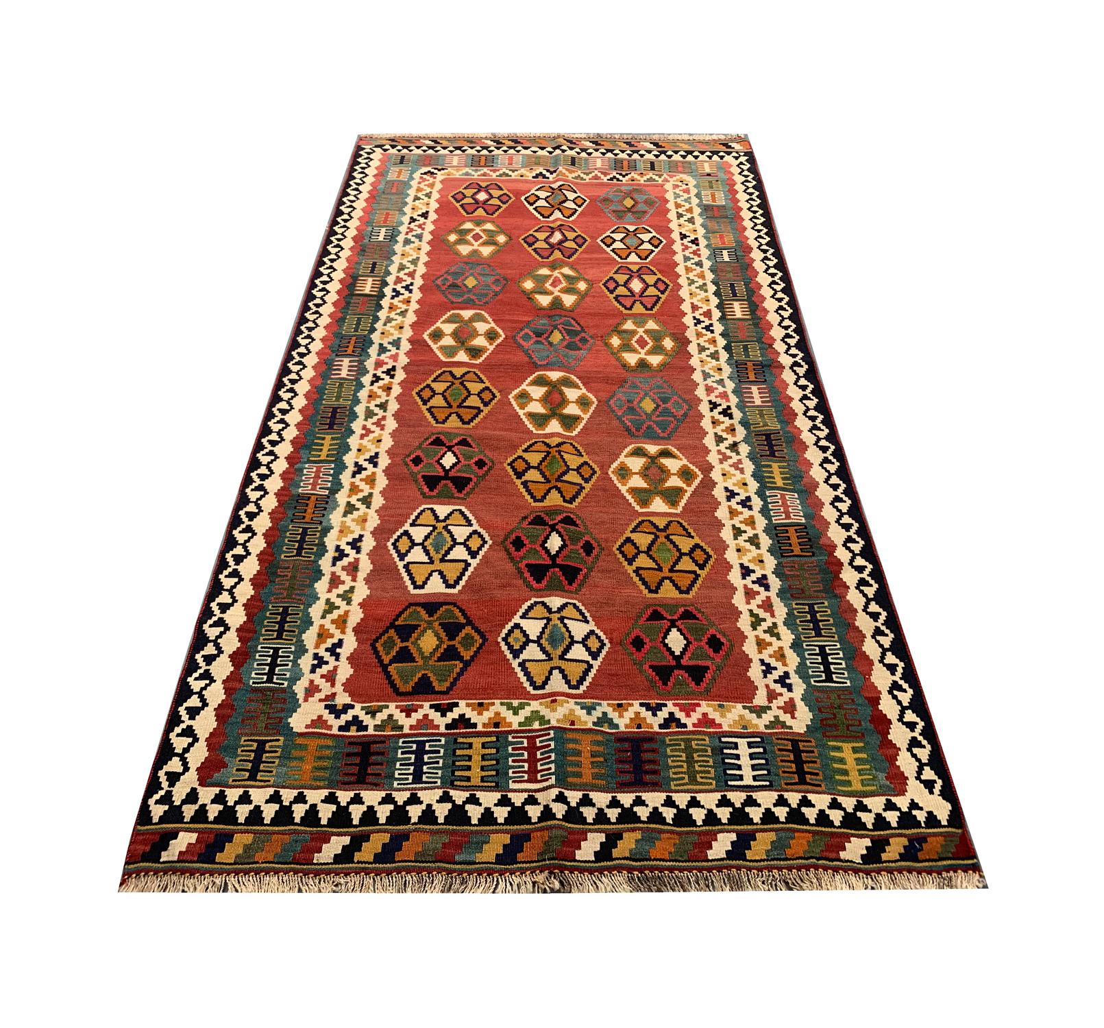 This fine, handwoven Caucasian Kilim was constructed in Azerbaijan and featured a fantastic tribal motif design. The central design has been woven on a red field and features, cream, green and black accent colours that make up the motif pattern. The