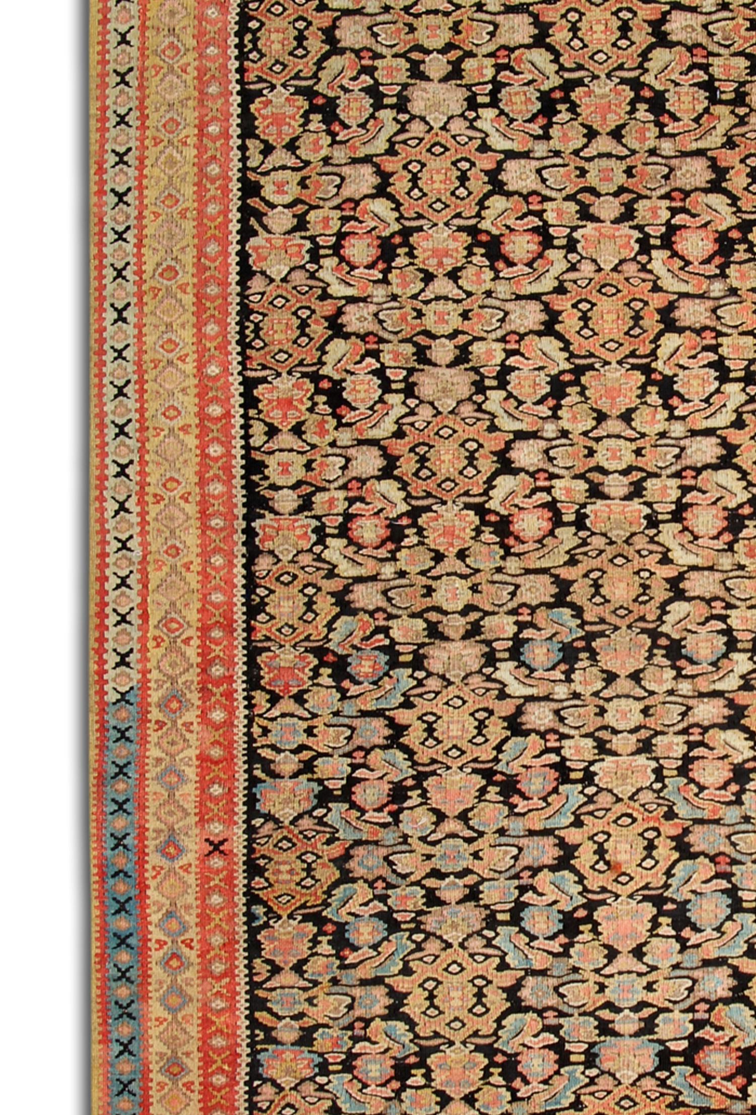 Ce tapis Kilim antique présente un magnifique motif floral sur toute sa surface, tissé de manière complexe avec de délicats détails floraux et géométriques. L'orange et le noir sont les principales couleurs utilisées, contrastant merveilleusement