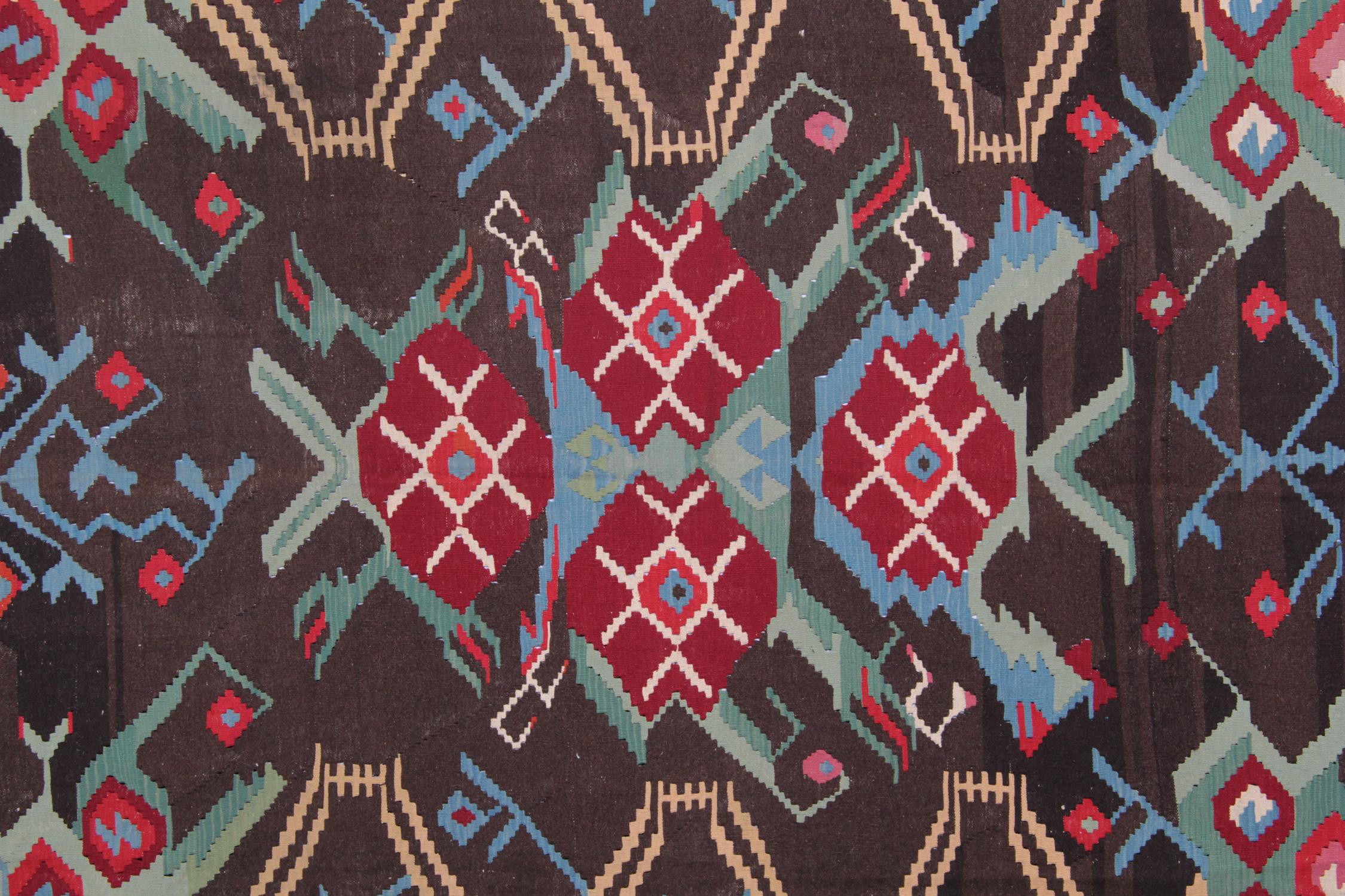 This colorful carpet rug is woven by very skilled weavers in Karabagh, who used the highest quality wool and cotton. The flat-weave rug has blue, green, grey, pink, brown and red colors. The dark brown background of this geometric rug has the same