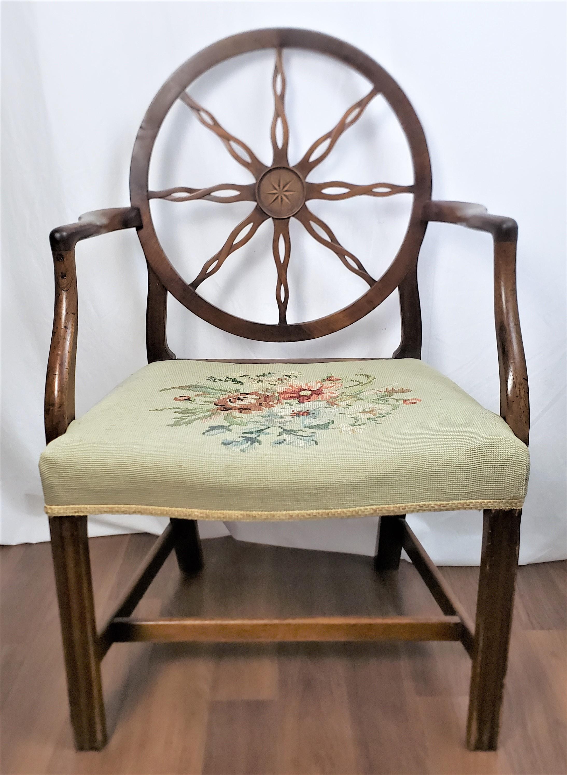 This antique armchair frame is unsigned, but presumed to have originated from England and date to approximately 1790 and done in the period King George III style. The chair is composed of walnut and features a large spoked wheel back with a stylized