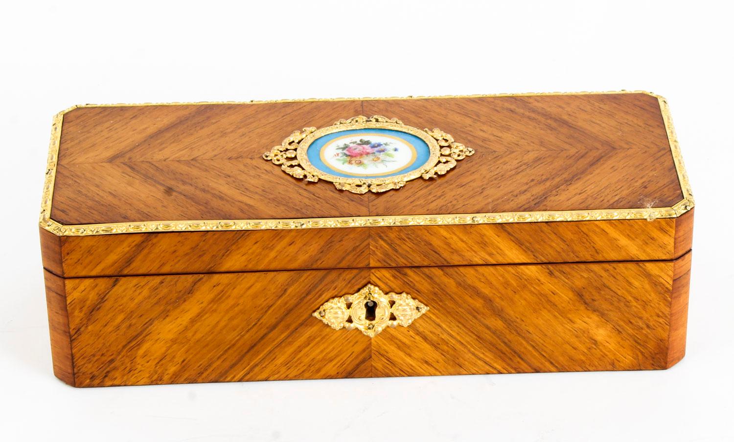 This is a beautiful antique French walnut jewel casket, circa 1870 in date.

Made from Kingwood with a decorative ormolu border and an inset central Sevres oval porcelain plaque, handpainted with a floral bouquet. With Royal Blue velvet lined