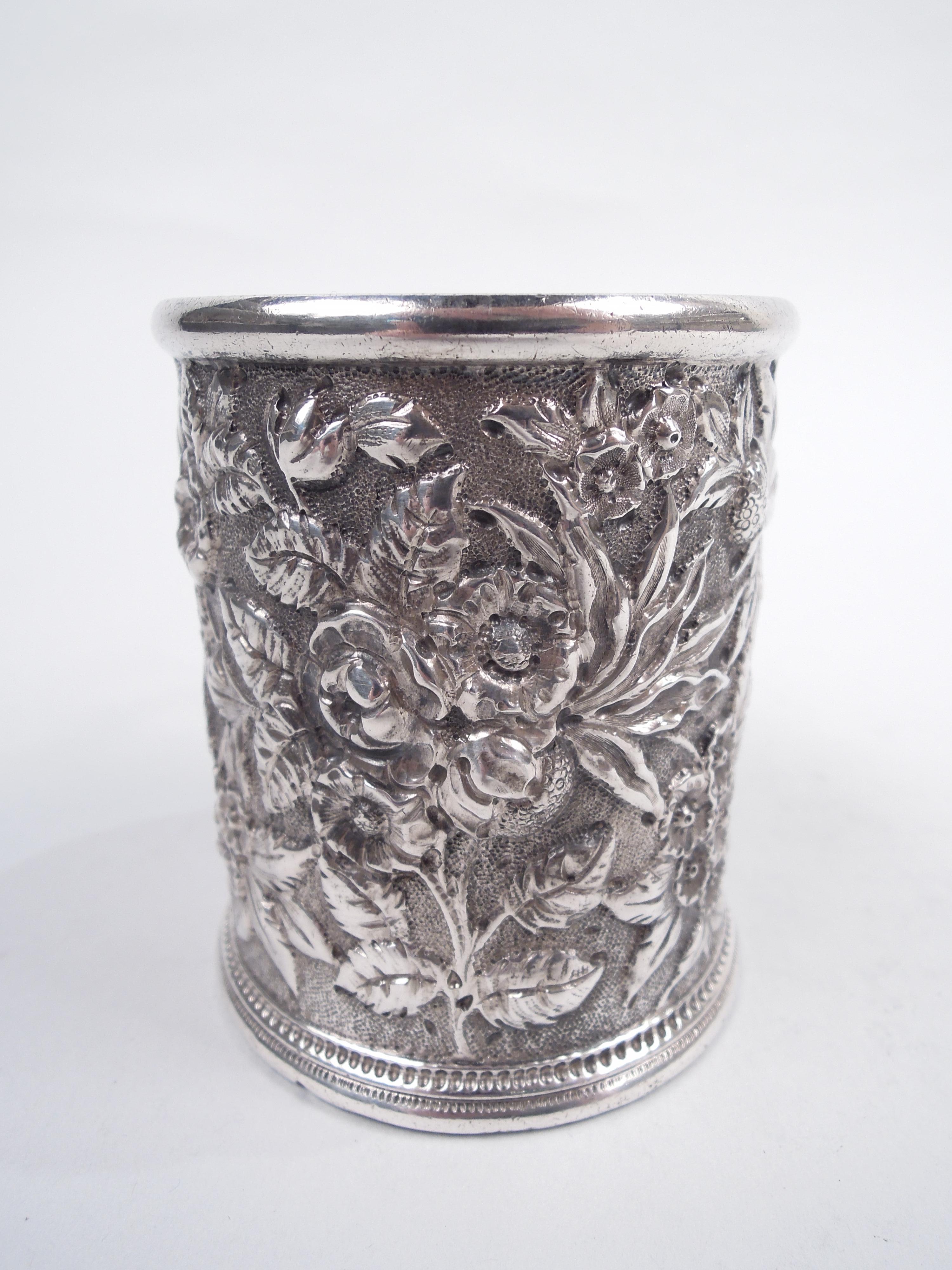 Victorian silver baby cup. Made by S. Kirk & Son in Baltimore. Straight sides with allover floral repousse on stippled ground. Cast and capped leaf scroll handle and pointille foot border. Fully marked including maker’s stamp (1846-61) and alloy “11