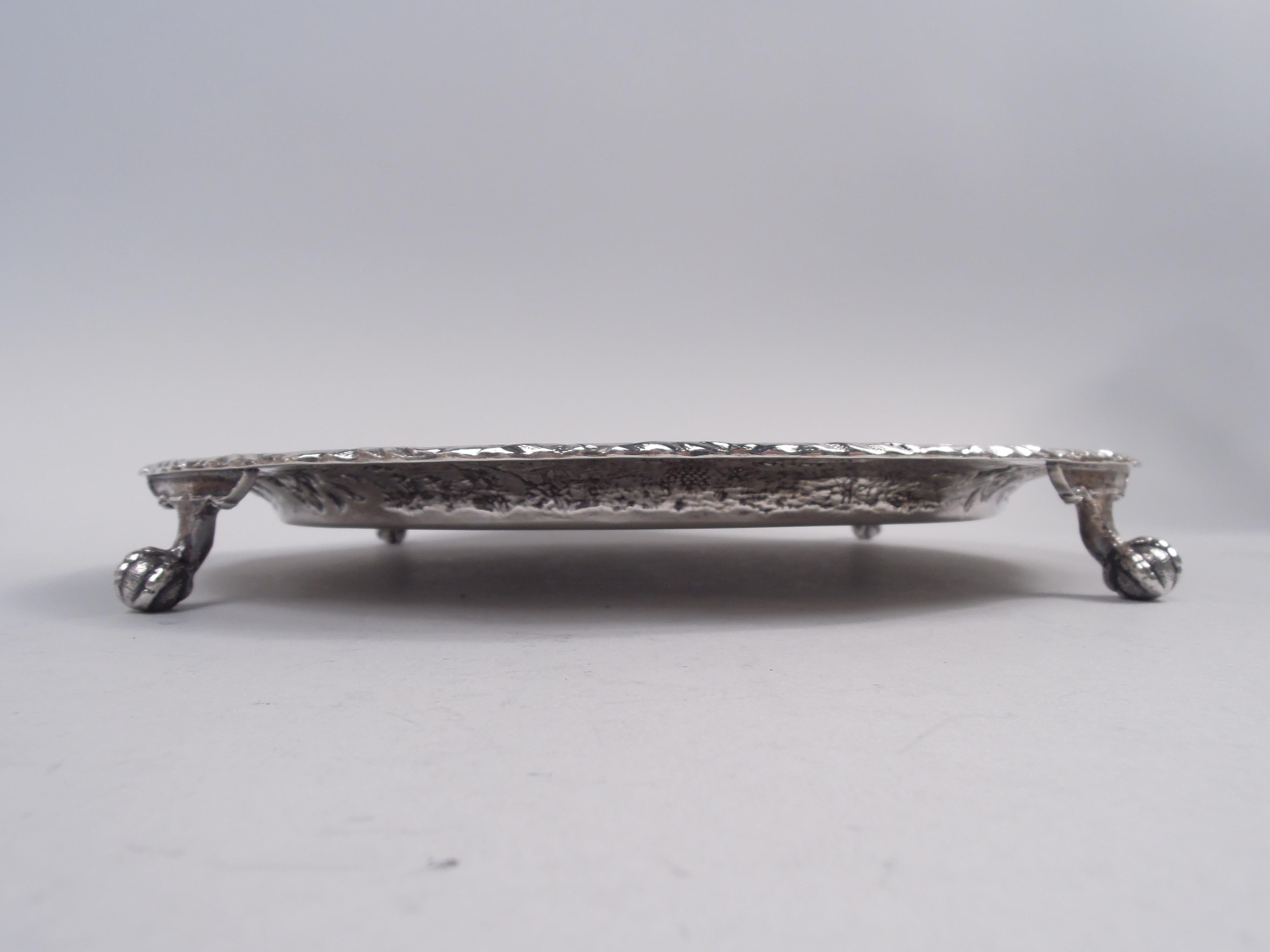 Edwardian sterling silver salver. Made by S. Kirk & Son Co. in Baltimore, ca 1910. Round well; central floral wreath engraved with interlaced script monogram; quatrefoil-inset diaper ground. Shoulder has chased and repousse pictorial tower and