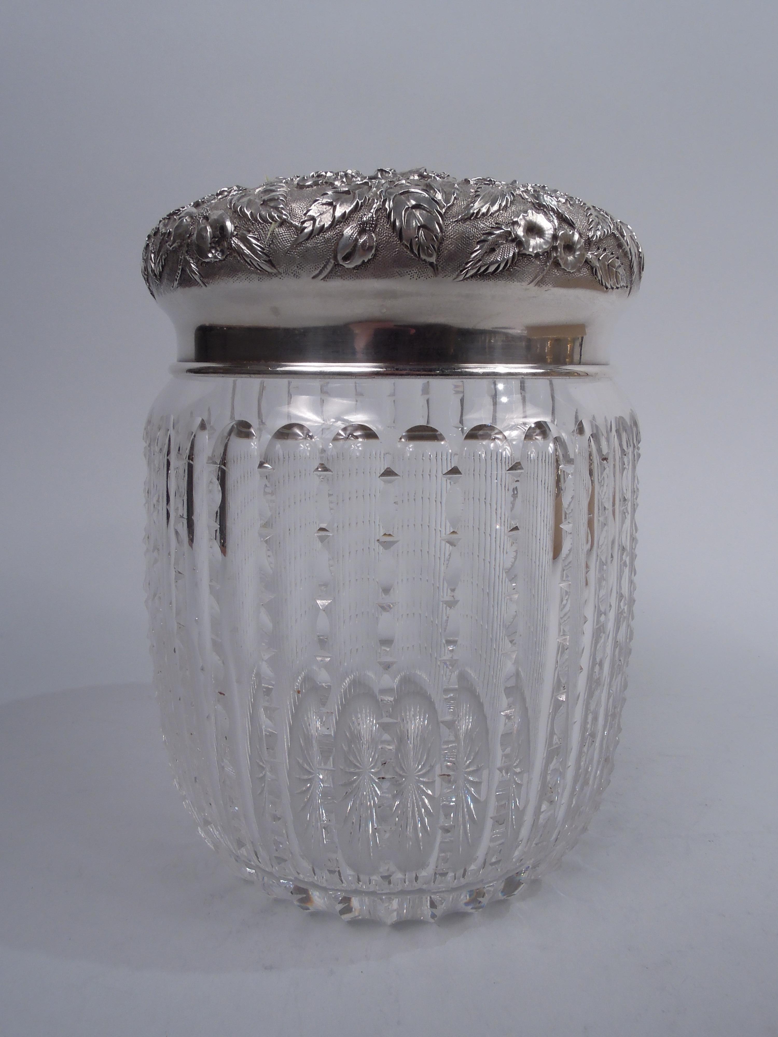 Edwardian glass tobacco jar with sterling silver cover. Made by S. Kirk & Son Co. in Baltimore, ca 1910. Jar has curved sides with cut bead-and-reel fluting and short inset neck; star cut to underside; Cover curved with allover floral repousse on