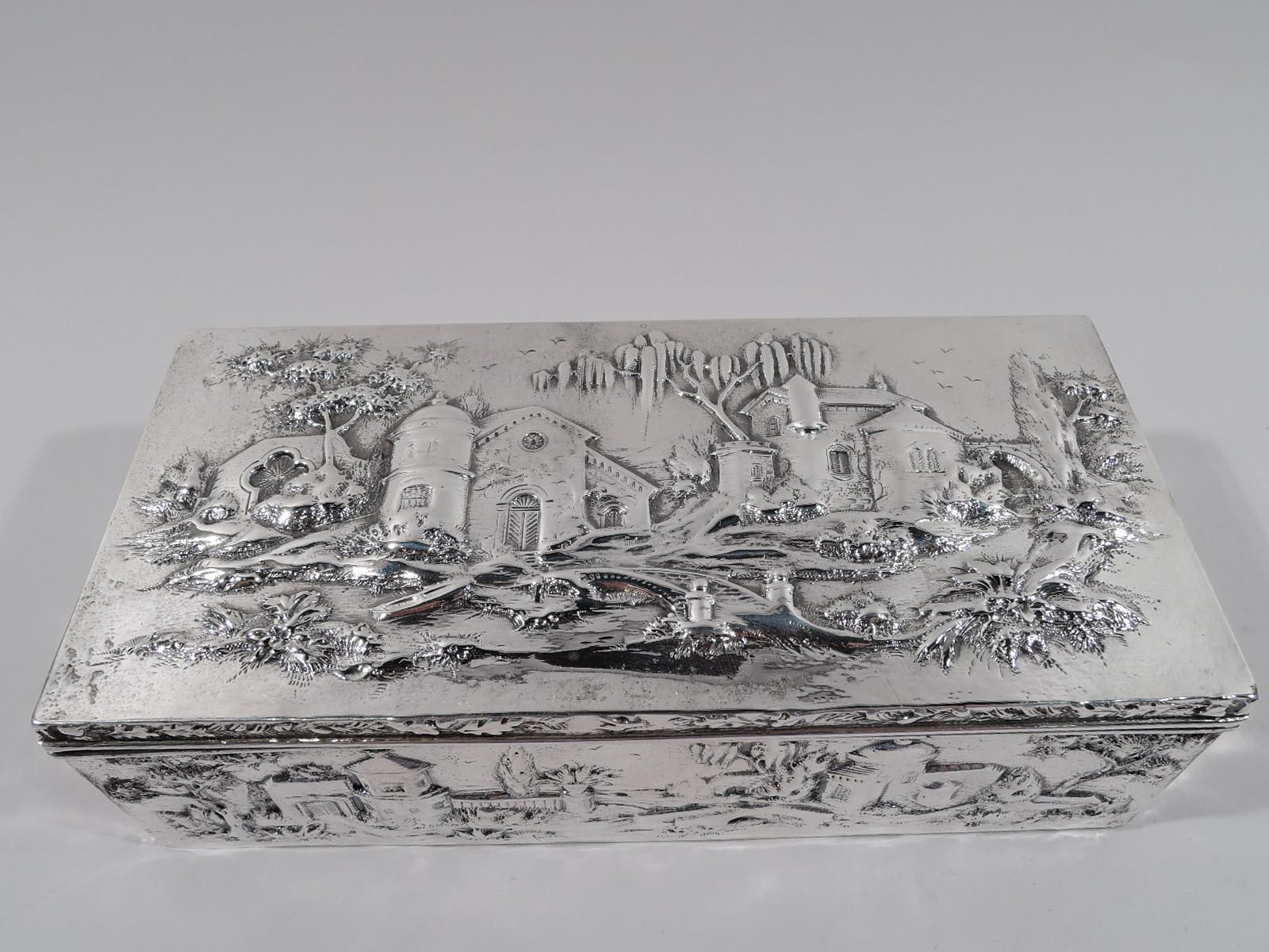 Edwardian sterling silver box. Made by S. Kirk & Son Co. in Baltimore. Rectangular with straight sides and hinged cover. Chased picturesque architecture: Turrets, towers, and footbridges in bosky landscape. Box interior cedar lined. Fully marked