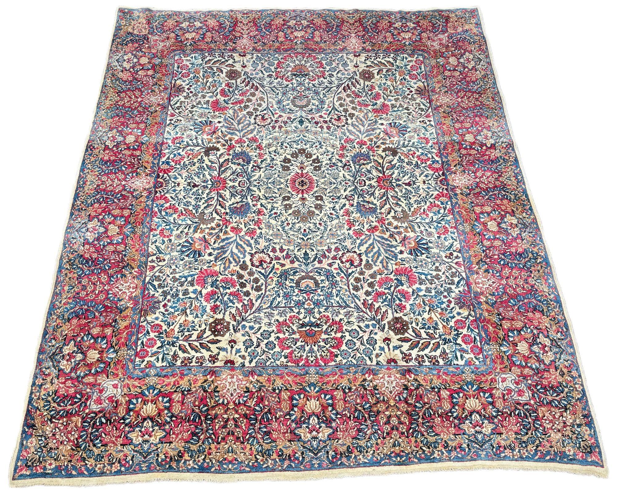 Un favoloso tappeto antico Kirman Lavar, tessuto intorno al 1910. Questo tappeto presenta un disegno floreale allover su un campo avorio e un bordo rosso lampone insolitamente ampio. Tessuto finemente con meravigliosi colori secondari di rosa, verde