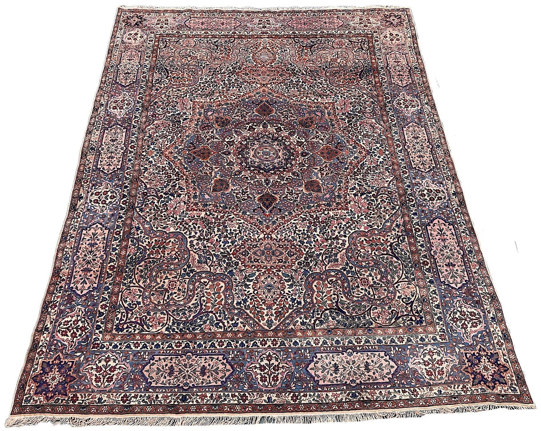 A stunning antique Kirman carpet, hand woven circa 1910. The design features a large indigo medallion on an ivory field of scrolling vines and flowers surrounded by an indigo border. Finely woven with soft, velvety wool and lovely secondary colours