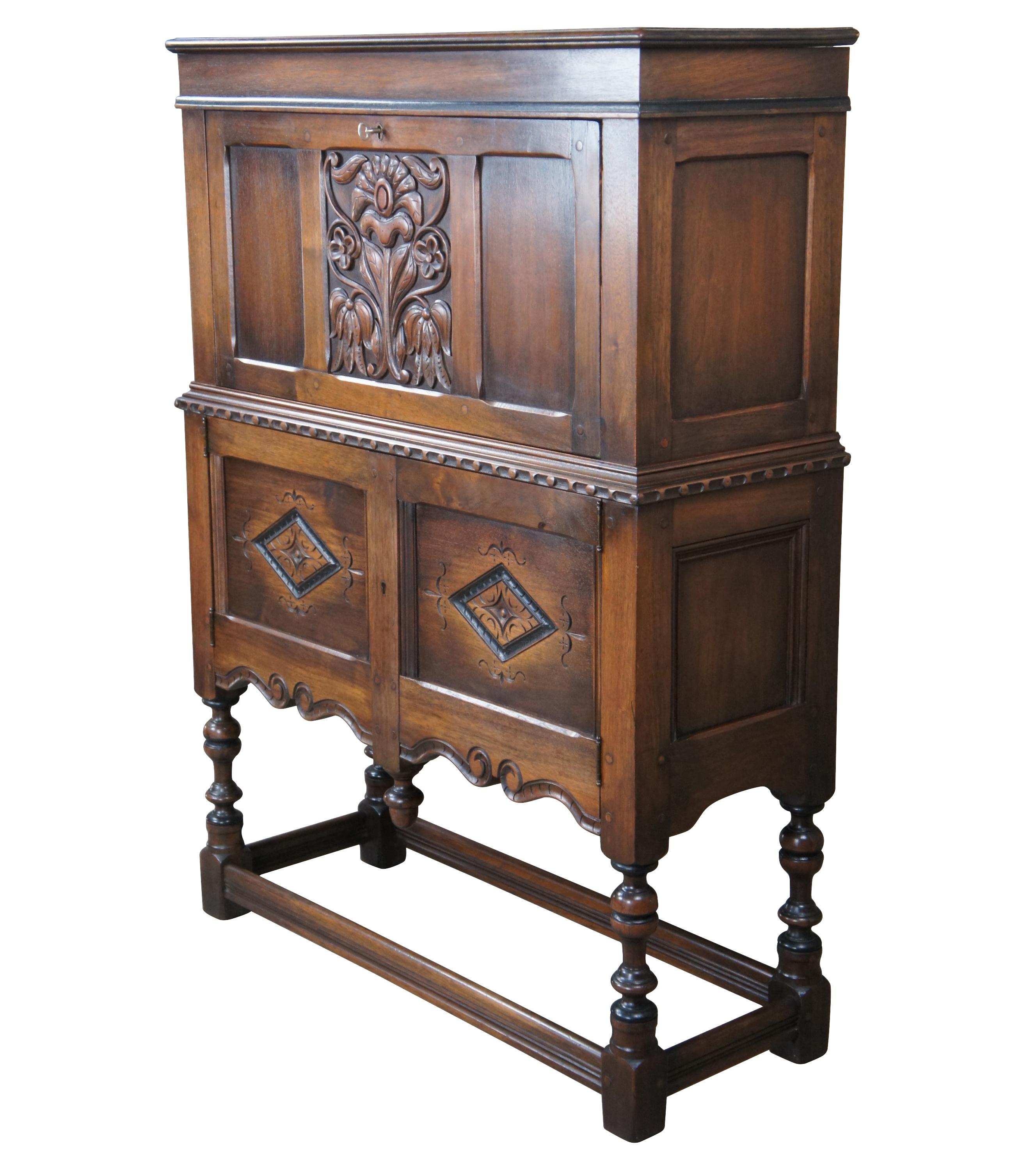 Extremely rare one of a kind early Kittinger Jacobean Revival fall front secretary writing desk. Made from American walnut with a carved and paneled front featuring a floral motif over diamond patterned lower doors. The secretary opens via lock to a
