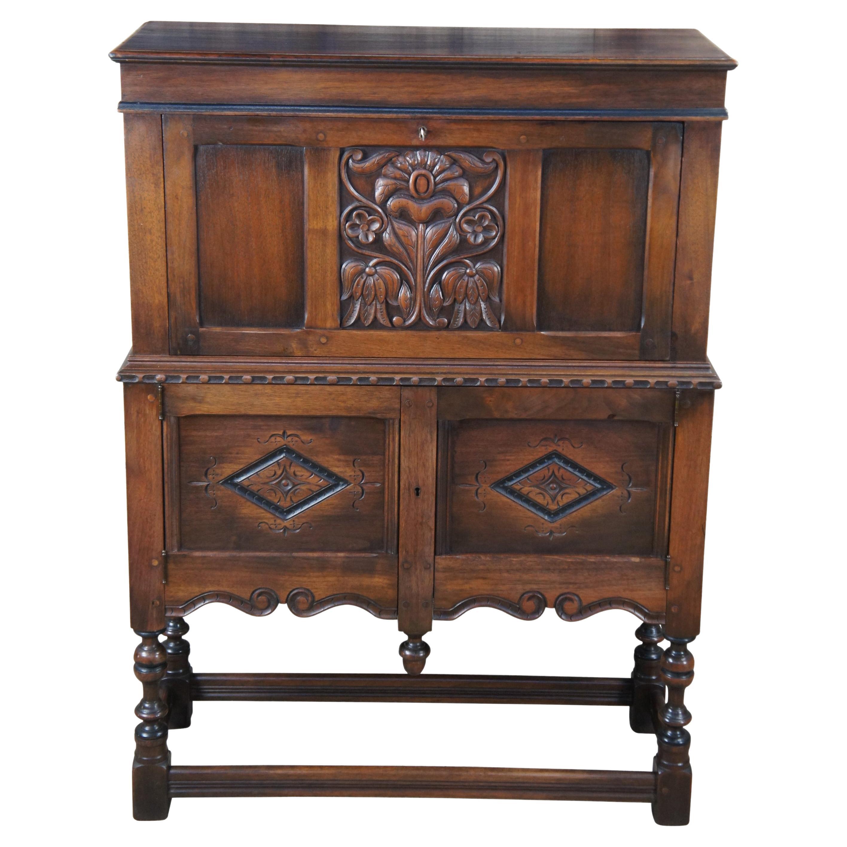 Extremely early Kittinger Jacobean Revival fall front secretary writing desk. Made from American walnut with a carved and paneled front featuring a floral motif over diamond patterned lower doors. The secretary opens via lock to a central drawer