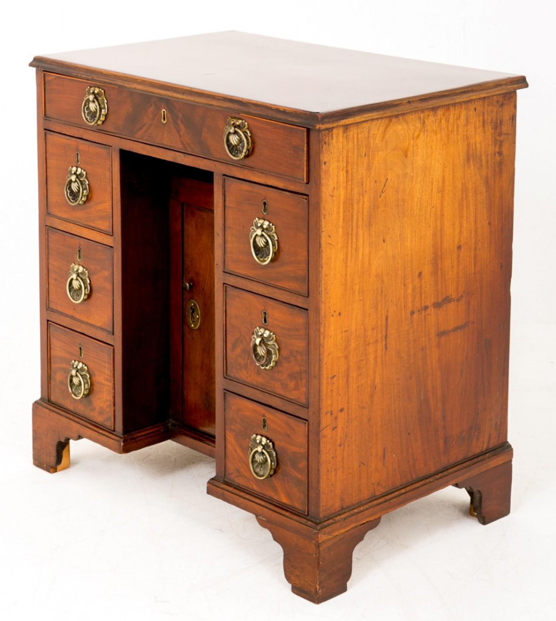 Georgian Mahogany Kneehole Desk.
Standing on bracket feet.
This piece features 7 Oak lined drawers and a central recessed cupboard.
Each drawer has a very pretty cast brass oyster shell ring pull handle.
The top with highly decorative timbers
