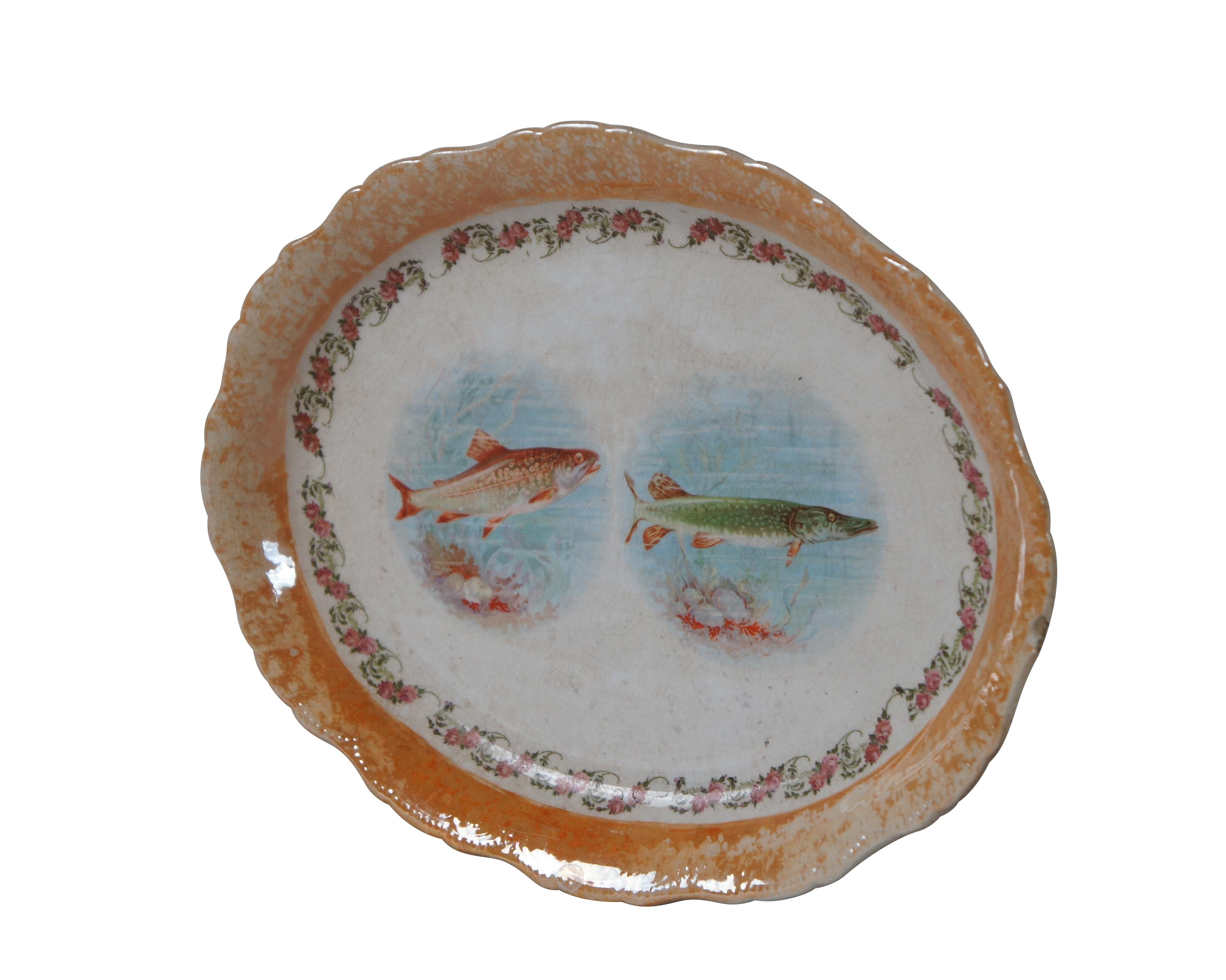 Late 19th - early 20th century semi-vitreous porcelain oval serving platter by Knowles, Taylor and Knowles. Features an iridescent orange border and transferware garland of roses around the images of a trout and a pike.

