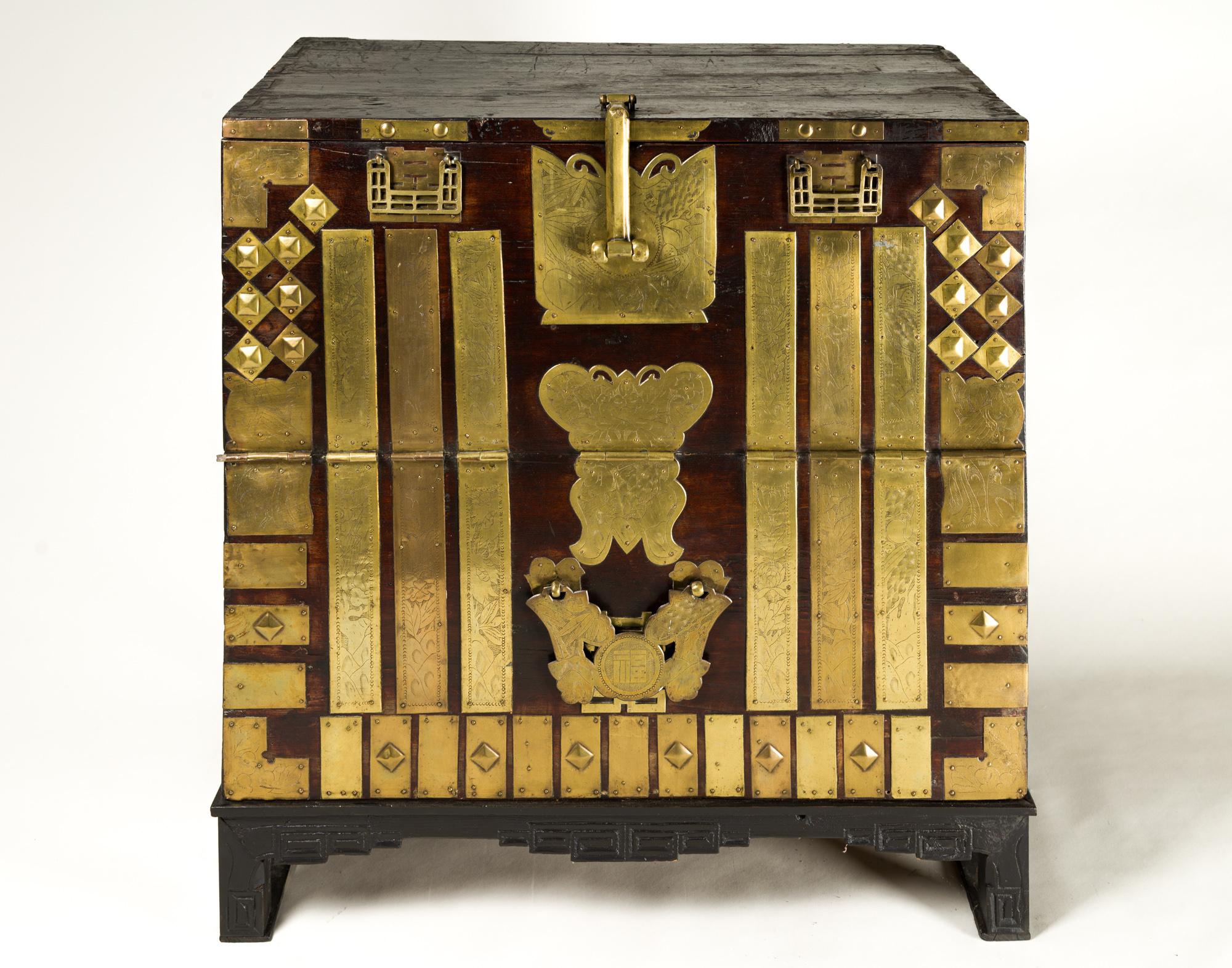 Antique Korean Blanket chest, elaborately decorated with ornate brass mounts in various geometric forms, some of which have incised landscapes and other imagery like pine and bamboo. The chest also has a butterfly shaped lock plate and is decorated