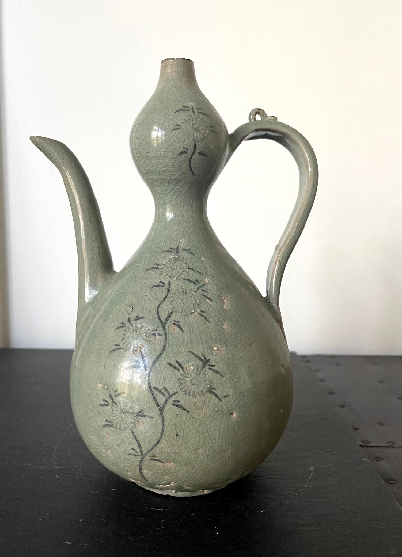 A Korean ceramic celadon ewer with black slip inlay design from Goryeo Dynasty (918 to 1392AD) circa 12-13th century. The vessel was used to contain and pour wine historically and it in a relatively rare form of 
