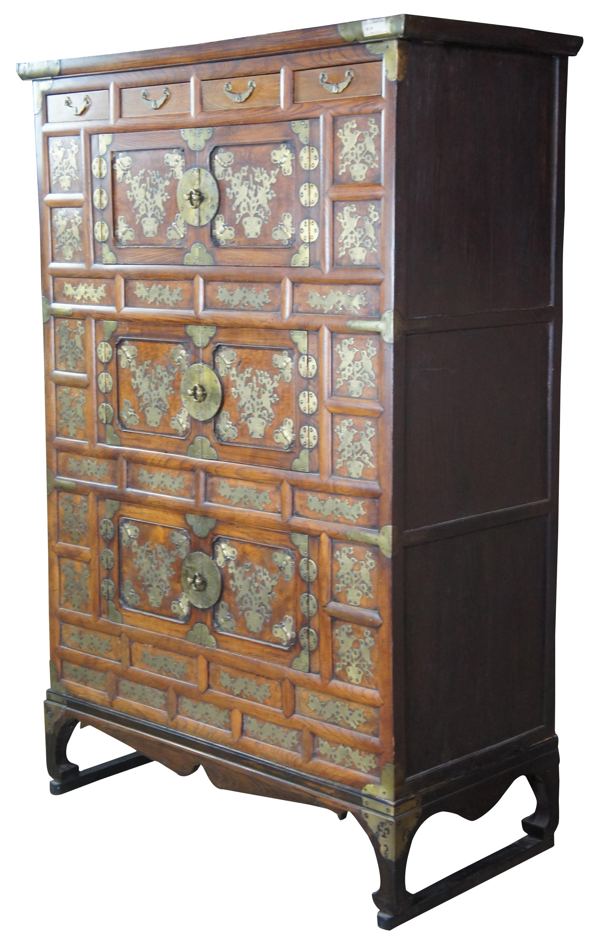 Fine & early 19th century Korean Tansu Nong Bandaji tallboy wedding chests or cabinet made of elmwood featuring ornate brass floral, butterfly, bird and sauwastika accents. The swastika symbol, ? (right-facing or clockwise) or ? (left-facing,